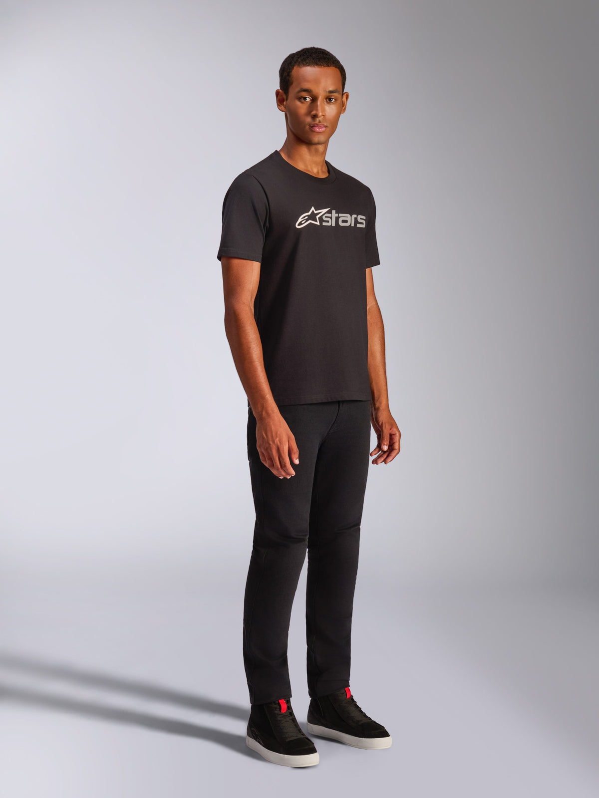 Alpinestars Blaze 2.0 CSF Tee, Short Sleeve T-Shirt, Black with White and Grey Logo Graphic, worn by male model with black pants and high-top sneakers, casual motorsport streetwear