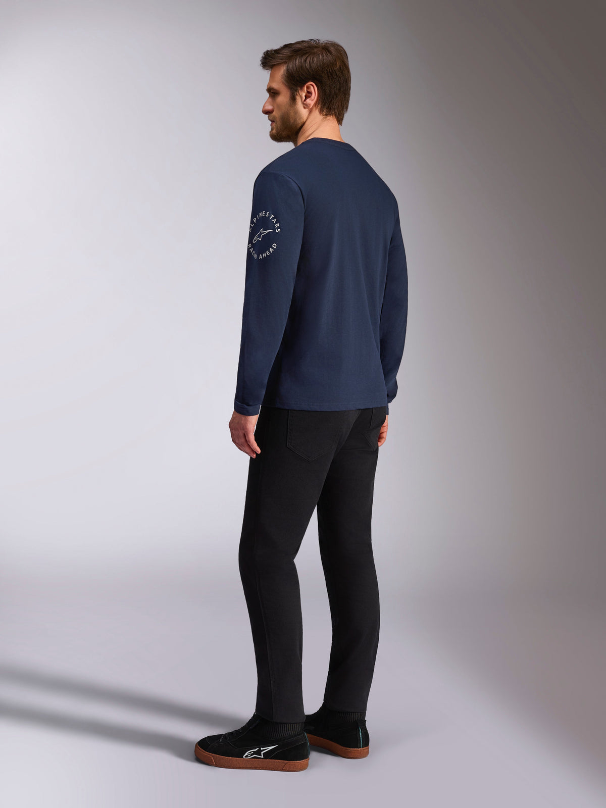 Alpinestars Mandatory CSF Tee - Long Sleeve, Navy, white circular logo on the sleeve, back-side view, worn with black pants and black sneakers, casual motorsport streetwear