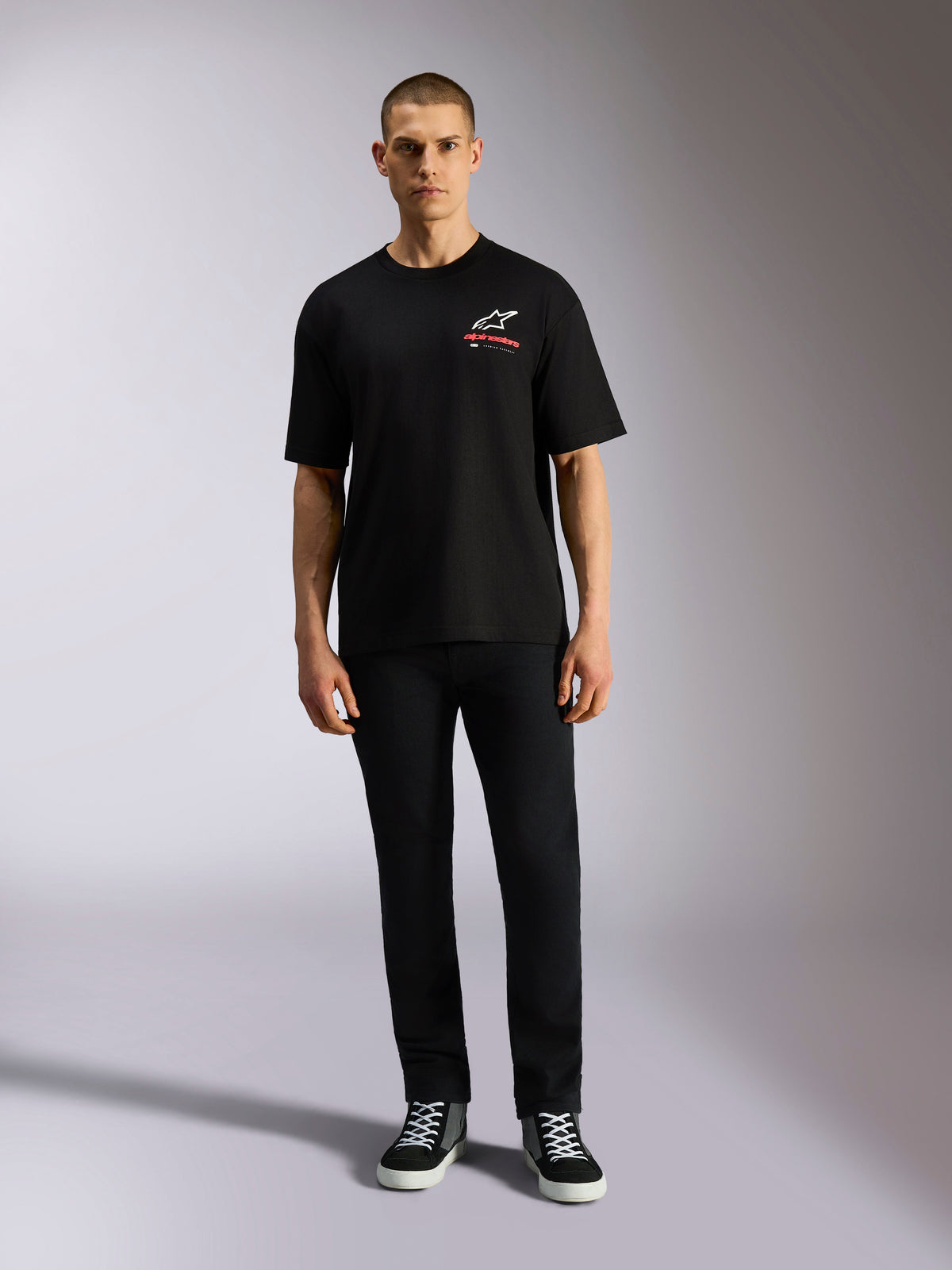 Alpinestars Overhang Oversized CSF Tee, Short Sleeve T-Shirt, Black, White Astars Logo with Red Text, worn by a model with black pants and sneakers, casual motorsport streetwear