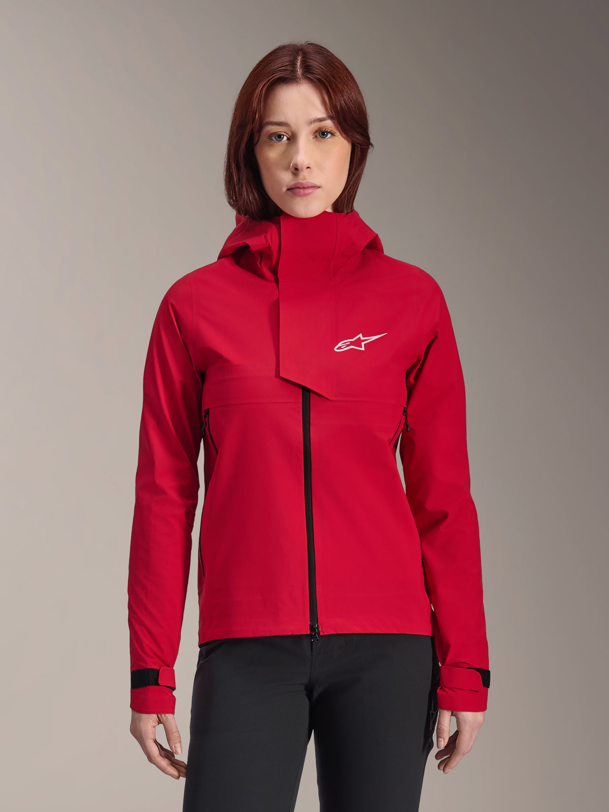 Alpinestars Stella A-Dura Elite Waterproof Jacket, Women's Mountain Bike Jacket, Red Fluo, hooded design with asymmetrical front flap, white Alpinestars logo on chest, adjustable black cuffs, worn on a female model with black pants