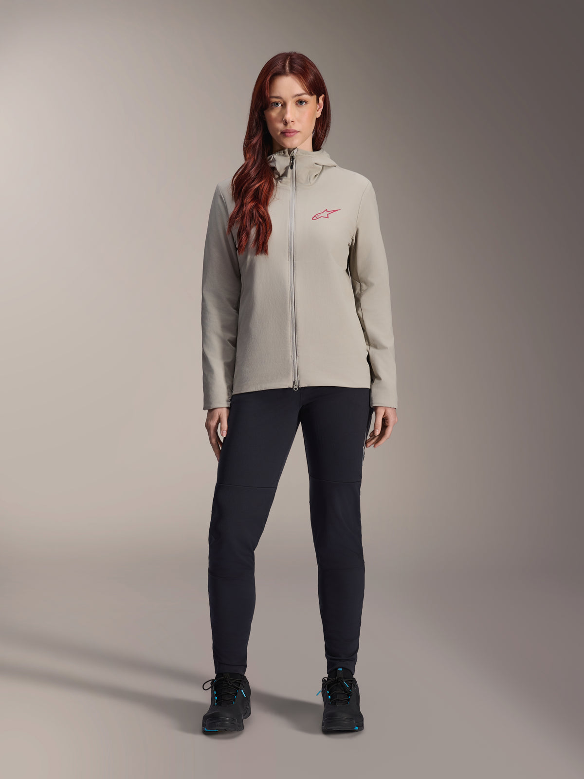 Alpinestars Woman Stella A-Dura Thermal Jacket, Mountain Bike Jacket, Titanium gray, worn with black technical pants and black footwear, featuring a fleece-lined hood and red chest logo, designed for cold-weather riding