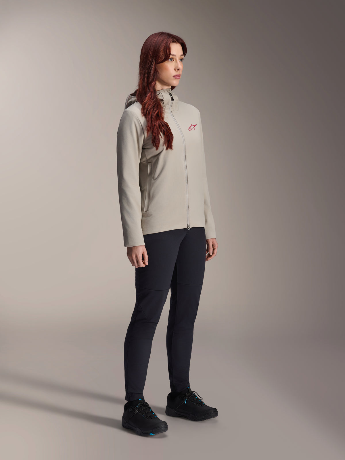 Alpinestars Stella A-Dura Thermal Jacket, Titanium gray, women's thermal cycling jacket with a red star logo on the chest, worn with black technical pants and black mountain bike shoes, studio shot for outdoor cycling apparel