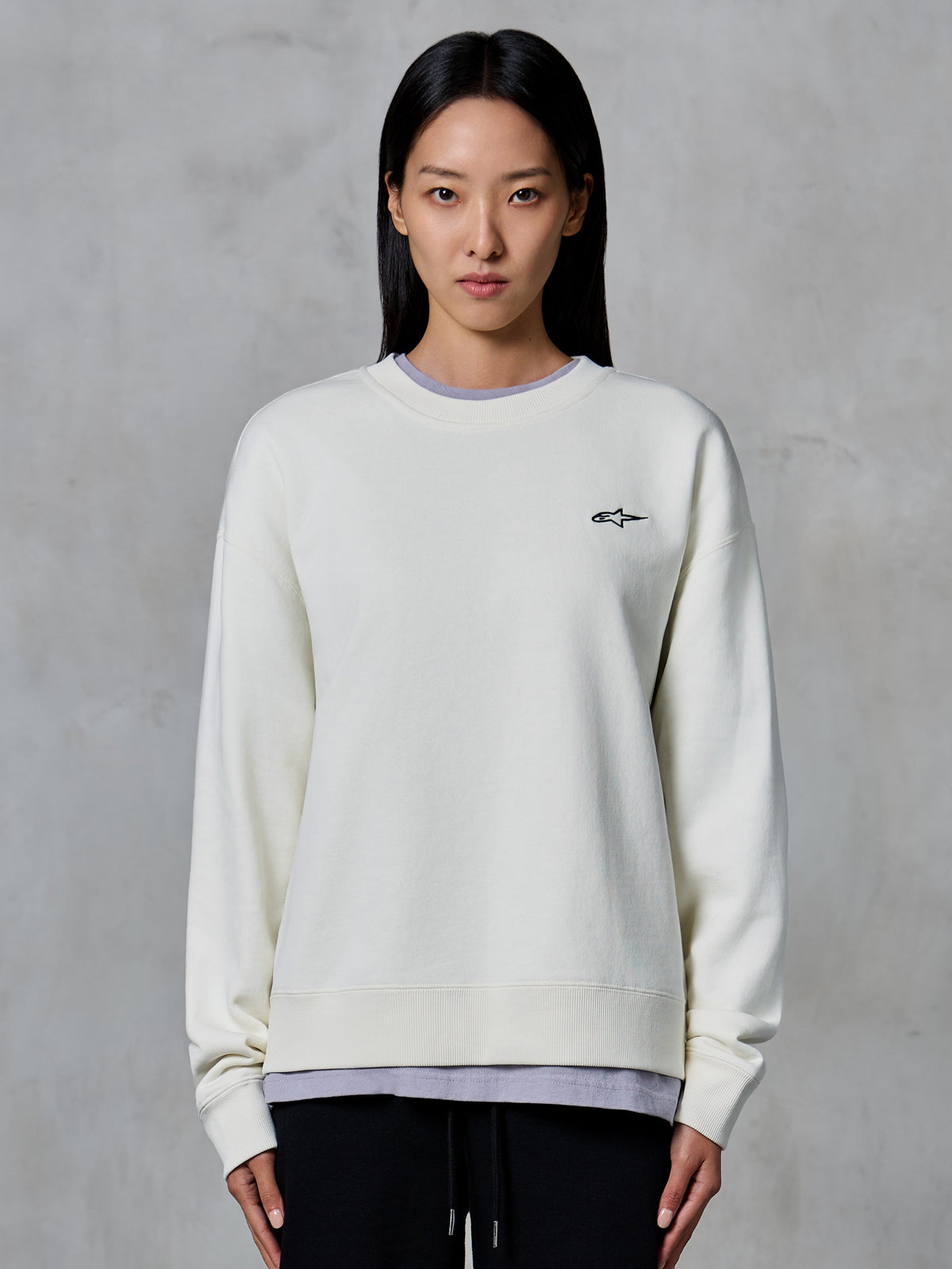 Alpinestars Essentials Ageless Crew, Crewneck Sweatshirt, Off White, featuring a small black Alpinestars logo on the chest, casual lifestyle apparel modeled on a woman