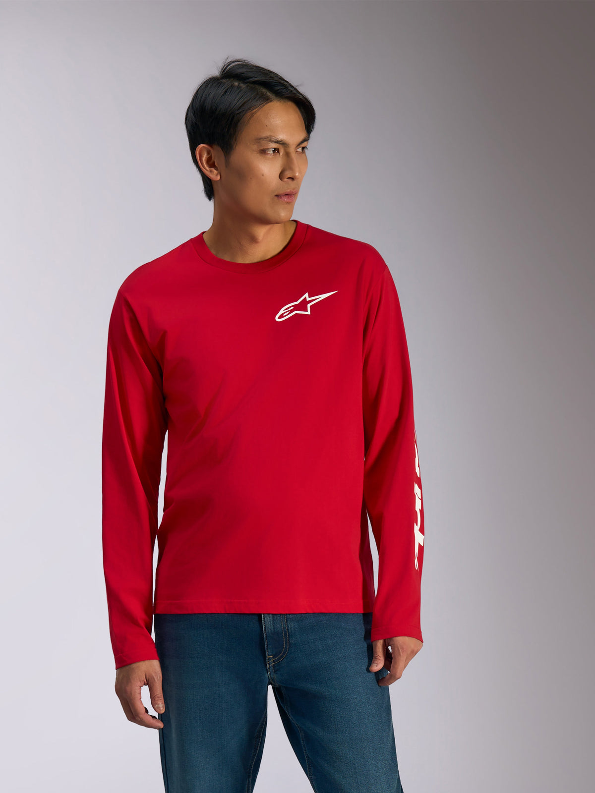 Alpinestars Trackside CSF Tee, Long Sleeve T-Shirt, Red with White graphics, white Alpinestars star logo on chest and white text on sleeve, worn with blue jeans, casual motorsport-inspired sportswear
