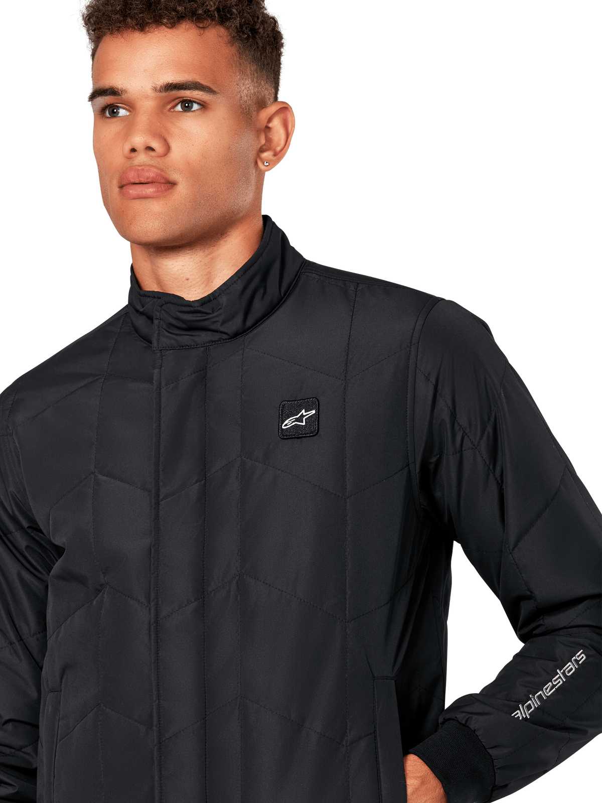 Alpinestars Precedent Jacket, Men's Quilted Sportswear Jacket in Black, close-up showing the low track collar, chest logo patch, and sleeve embroidery, featuring an iconic angled quilt pattern for a motorsport-inspired look.