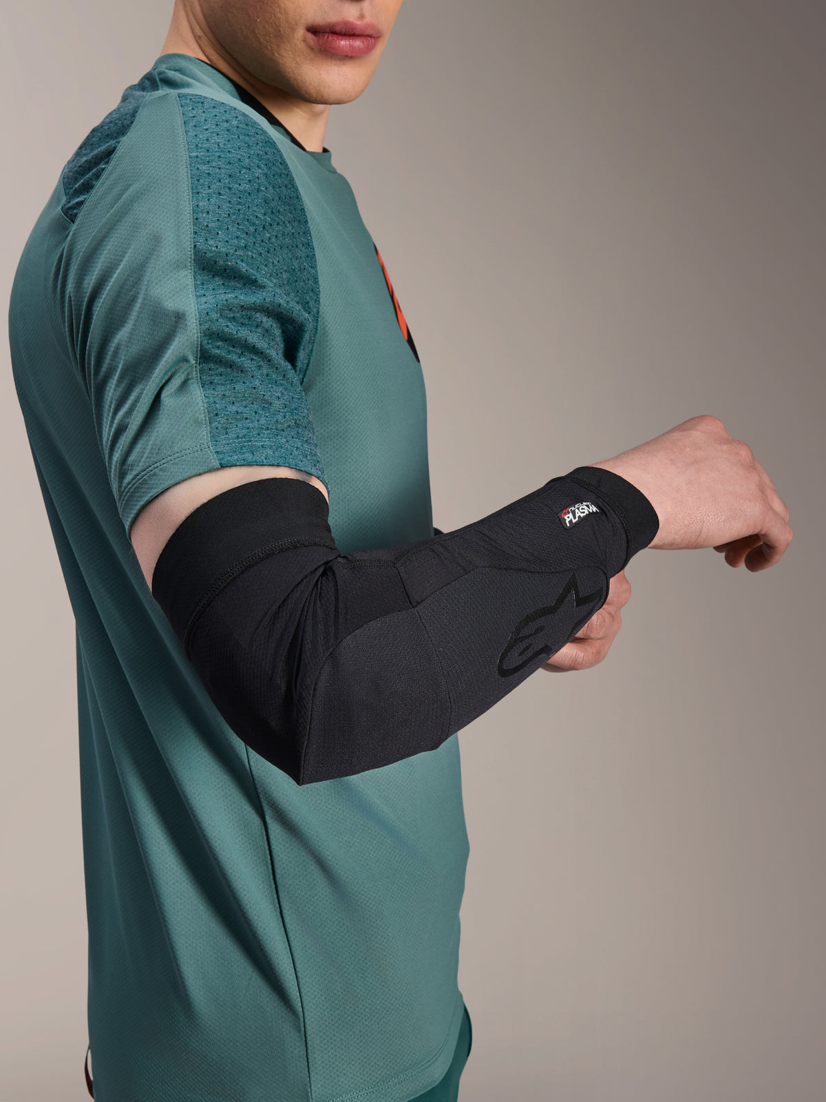 Alpinestars A-Motion Plasma Elbow Sleeve, Cycling Elbow Protector, Black, worn by a rider with a teal jersey, featuring the Alpinestars logo and Nucleon Plasma branding, sleek and breathable design for MTB protection
