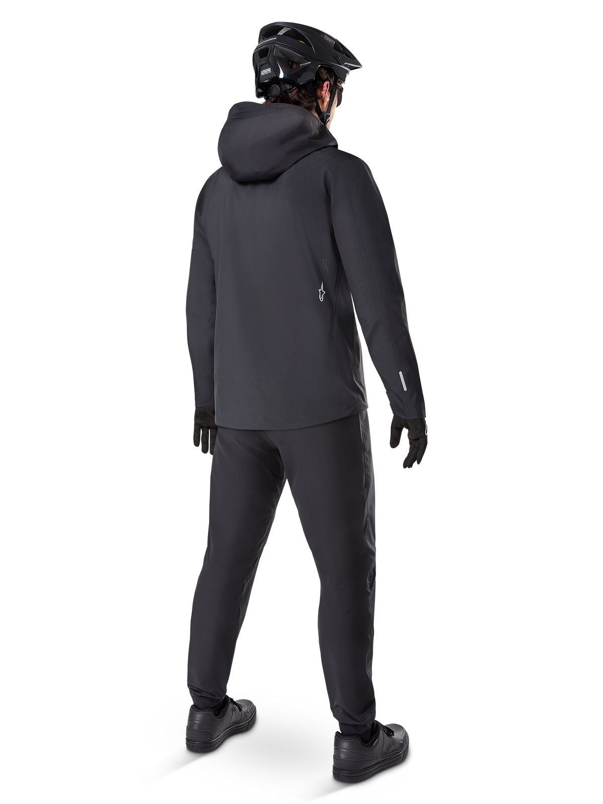 Alpinestars A-Dura Waterproof Pants, MTB pants, Black, shown from the rear on a rider wearing a full black mountain biking outfit including a hooded jacket and helmet, durable waterproof gear for muddy trails