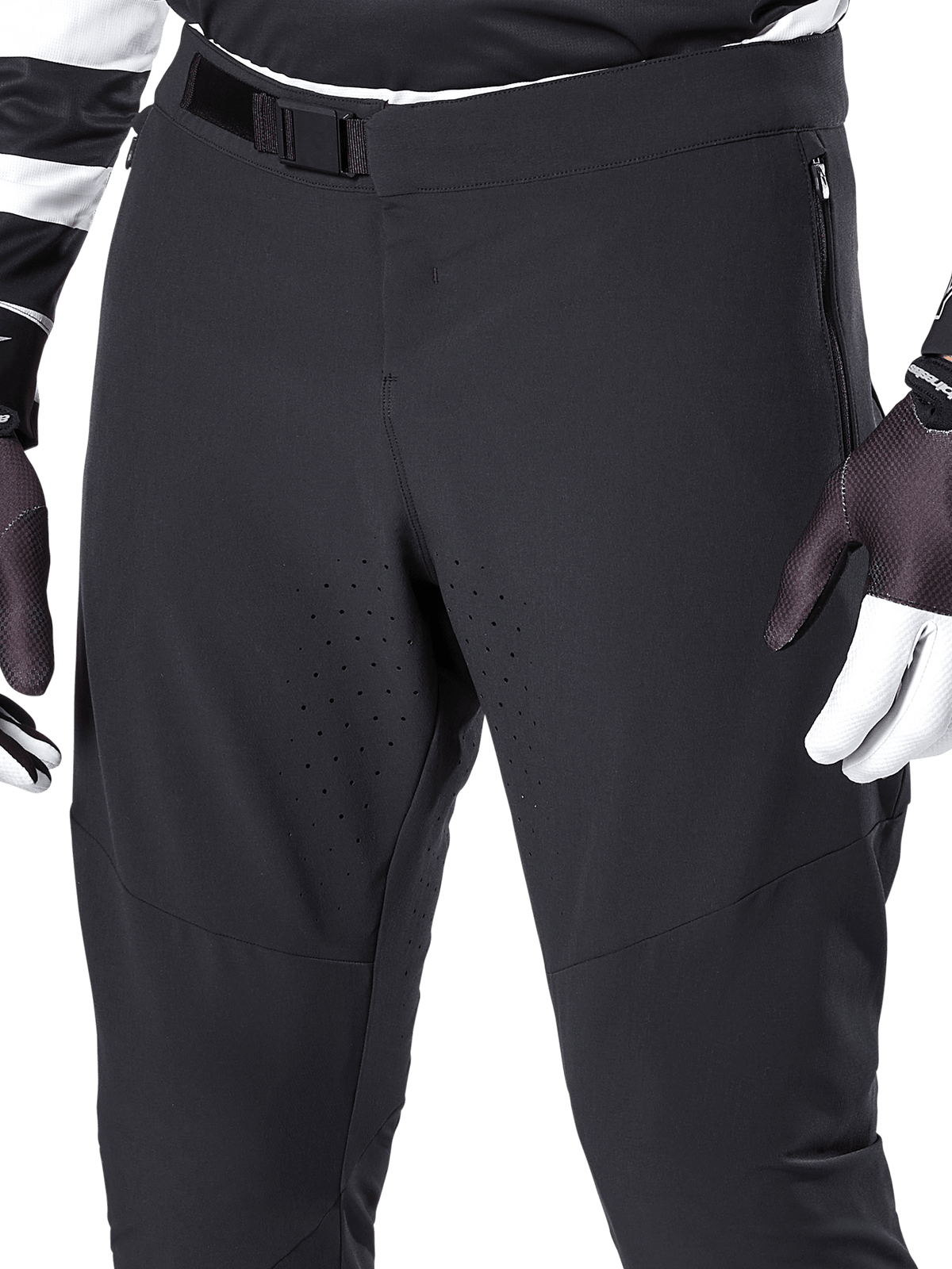 Alpinestars A-Aria Elite Pants, Black mountain bike pants, close-up of front waist and thighs featuring magnetic buckle closure and laser-cut ventilation holes, paired with cycling gloves