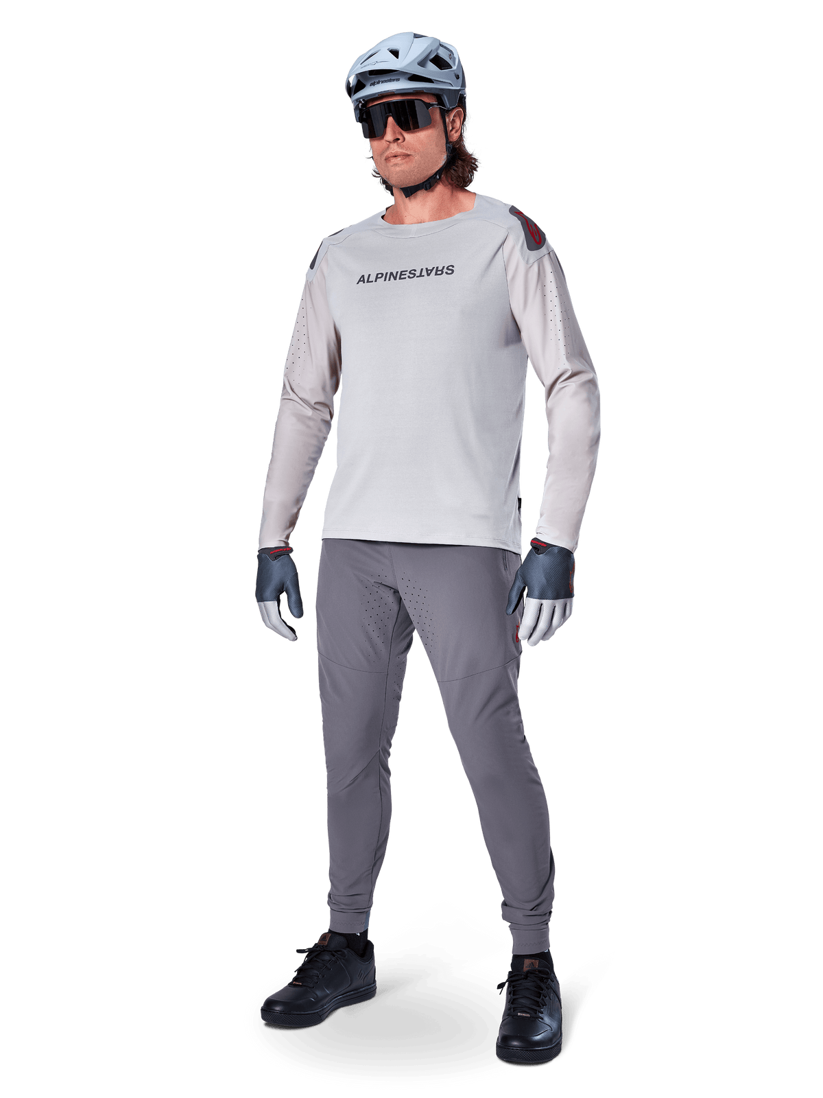 Alpinestars A-Aria Elite Pants, Dark Gray MTB Pants, worn by a rider with a light gray long-sleeve jersey and gray helmet, featuring laser-cut ventilation on the thighs and a tapered performance fit for mountain biking.