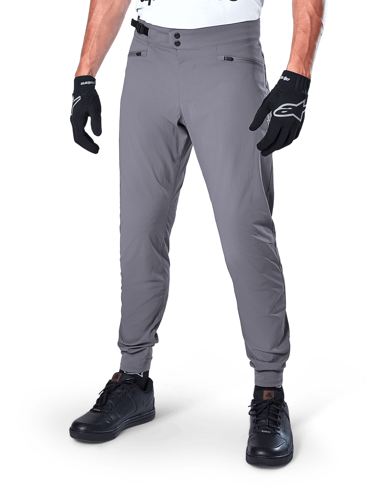Alpinestars A-Dura Pants, Dark Gray MTB Pants, featuring double snap waist closure and zippered pockets, elasticated cuffs, worn with black cycling gloves and black sneakers