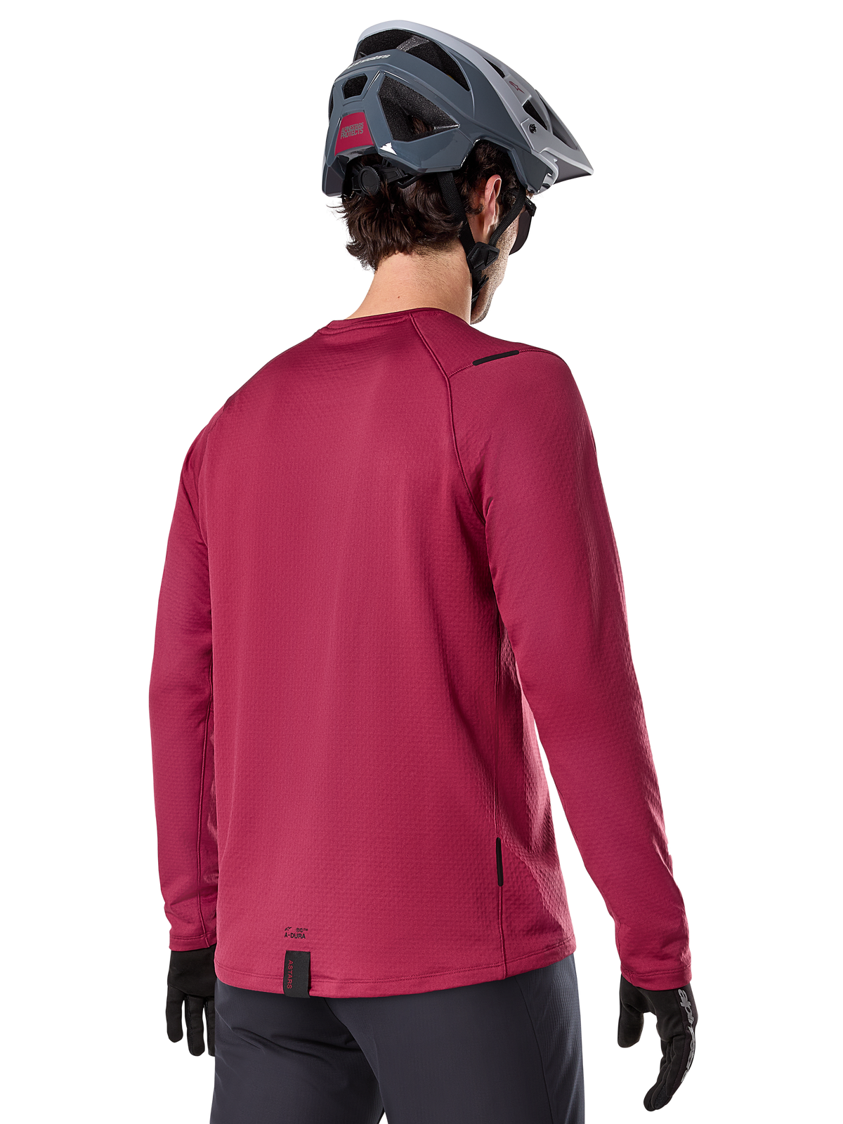 Alpinestars A-Dura Thermal Jersey, Long Sleeve Mountain Bike Jersey, Burgundy, back view on model wearing a grey MTB helmet and black gloves, featuring an extended drop tail and small logo details, designed for cold-weather trail riding.