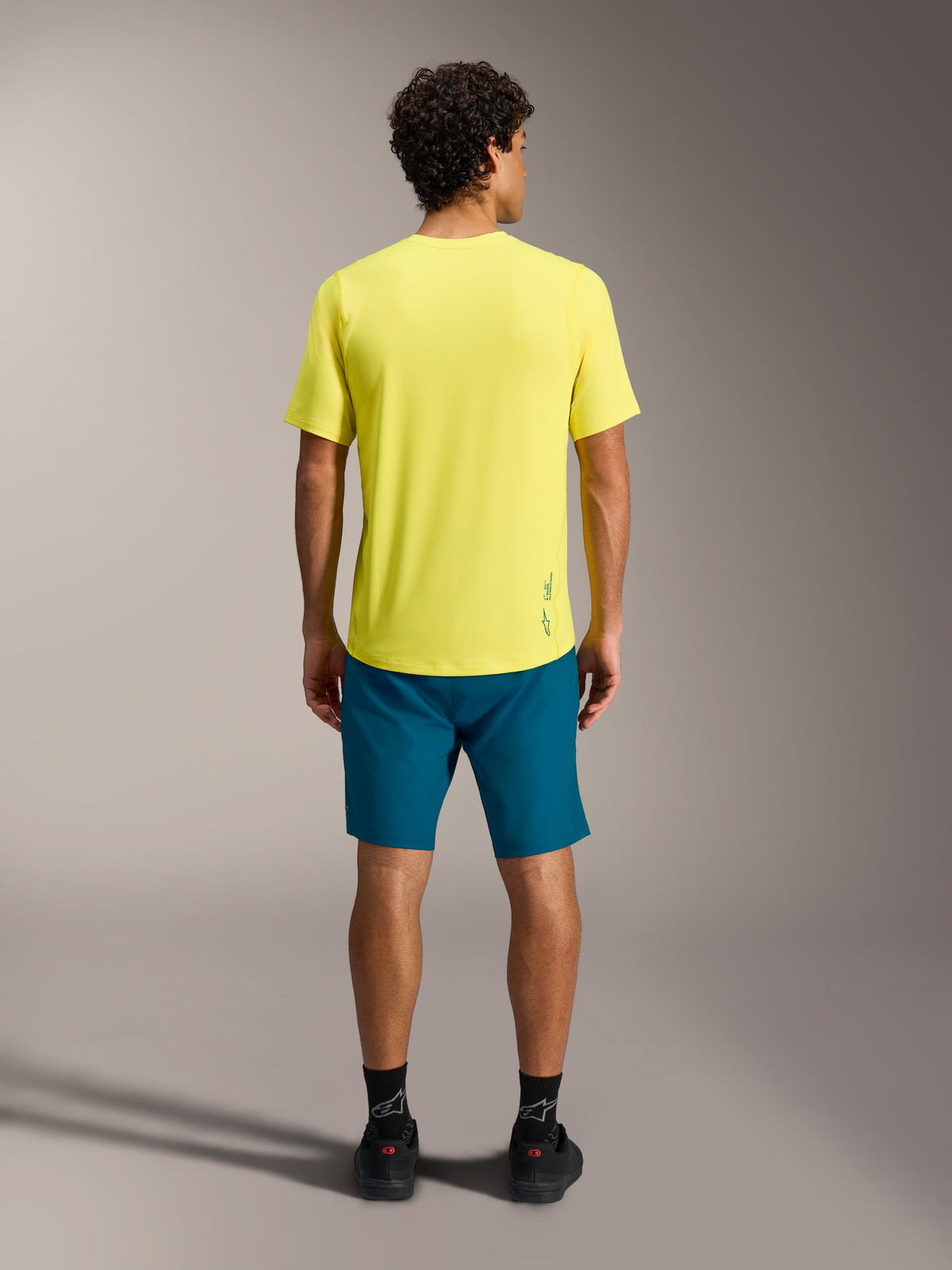 Yellow A-Dura Ride SS Jersey paired with blue-green A-Dura Ride Shorts, seen from behind for MTB performance apparel.
