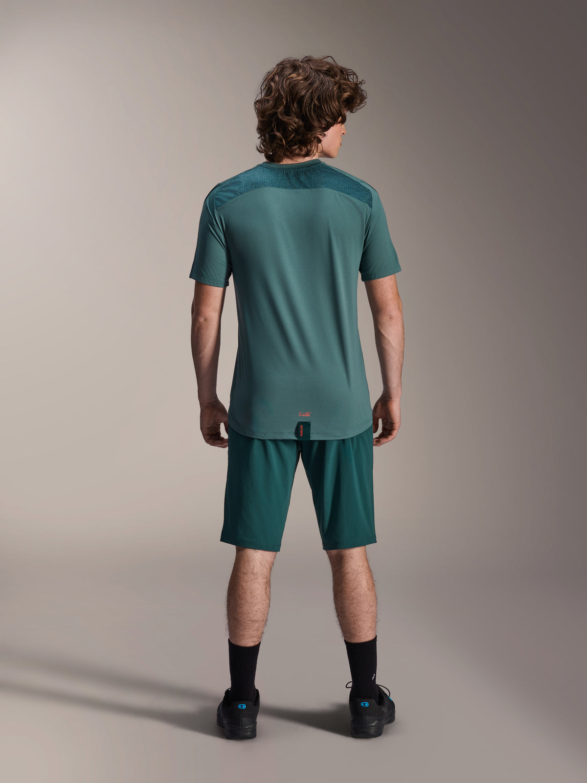 Alpinestars A-Dura Shorts and A-Dura Lipan SS Jersey, Dark Pine green, back view on a model, performance mountain bike apparel featuring short sleeve jersey and matching shorts, off-road cycling outfit