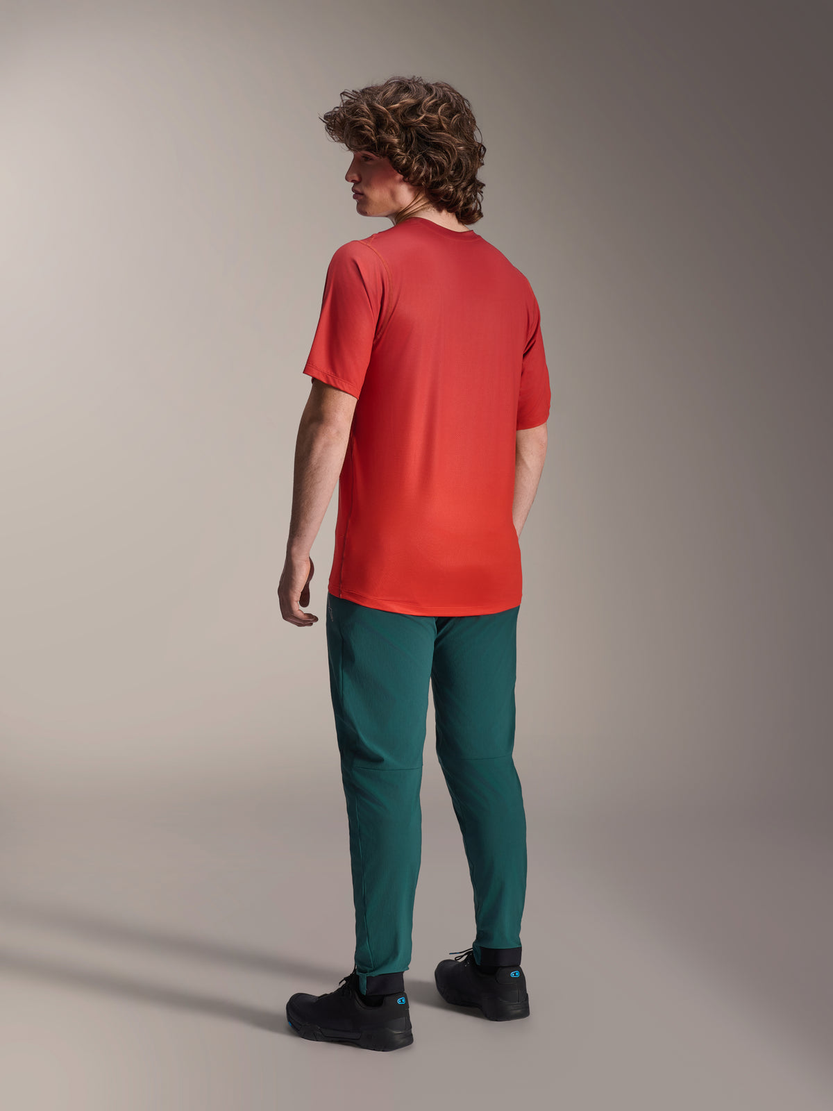 Model viewed from behind wearing Alpinestars A-Dura Pants in Dark Pine green and a red A-Dura Rise Short Sleeve Jersey, featuring a regular fit and elasticated cuffs, performance mountain bike apparel for off-road riding