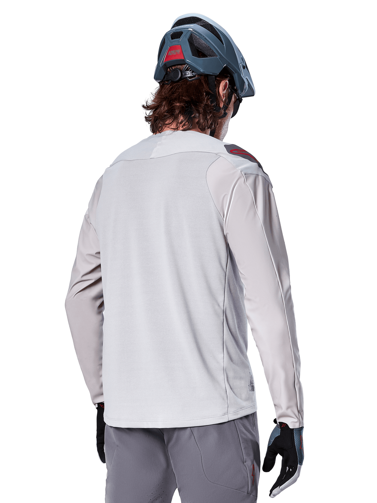 Alpinestars A-Aria Polartec Switch Long Sleeve Jersey, Light Gray, seen from the back on a rider, worn with a blue mountain bike helmet and gray pants, performance mountain bike apparel for off-road trails