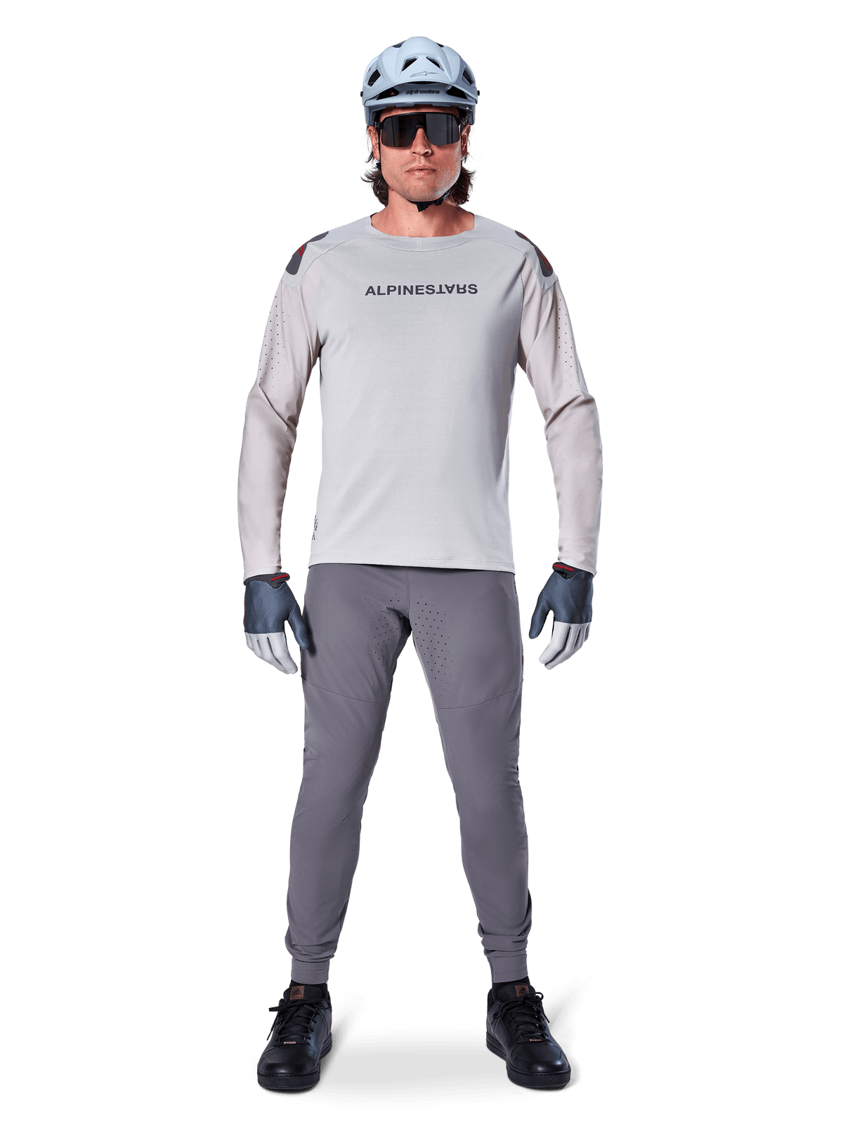 Alpinestars A-Aria Polartec Switch Jersey, Long Sleeve, Light Gray, worn by a male mountain bike rider with dark gray MTB pants, light blue helmet, and sunglasses, featuring chest branding and laser-perforated ventilation on the sleeves, complete off-road riding outfit.