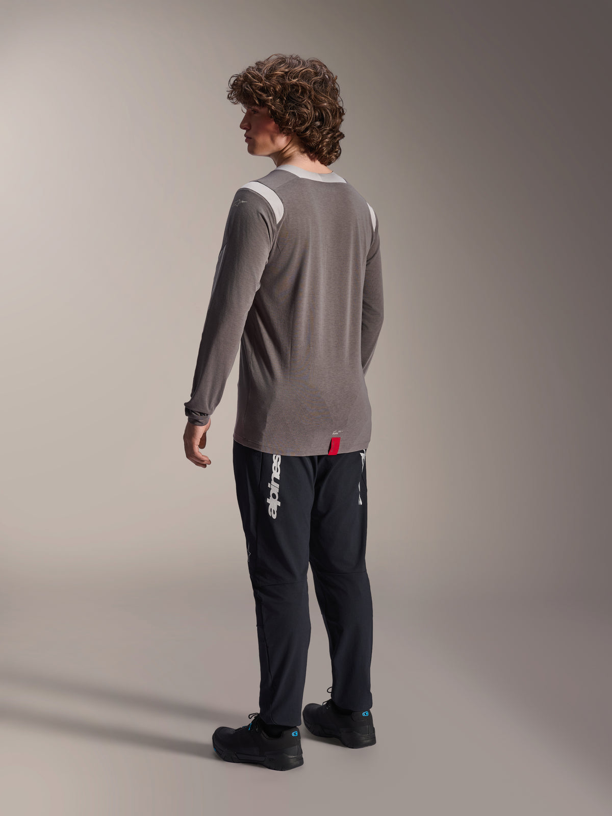 Alpinestars A-Dura Dri-Wool Long Sleeve Jersey in grey paired with A-Dura Elite Pants in black, rear view of model, featuring white Alpinestars logo on the leg, technical mountain bike gear for off-road riding