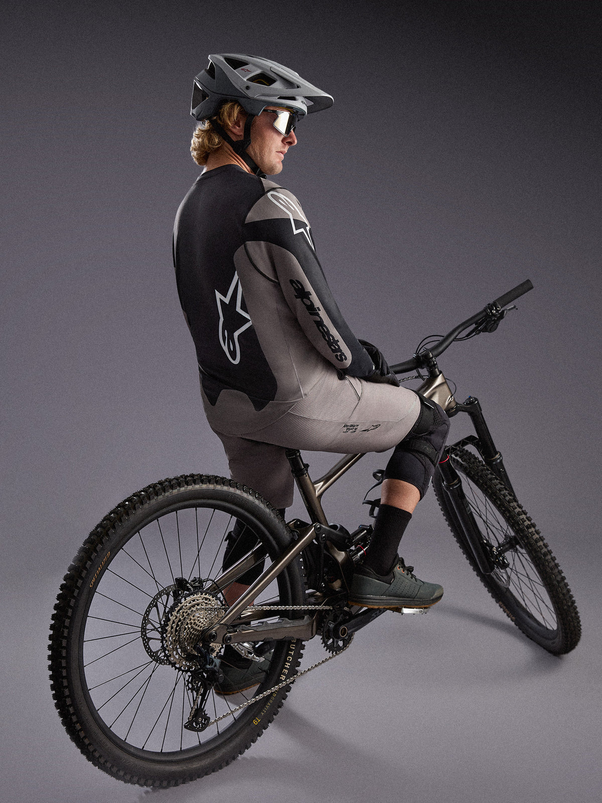 Gray A-Dura Race Long Sleeve Jersey on a mountain biker, featuring bold Alpinestars logos and performance stretch fabric.