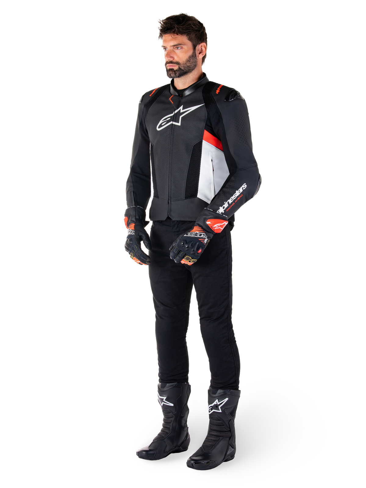 Alpinestars Missile V3 Airflow Leather Jacket, Black White Red Fluo, worn by a male model with black pants, black racing gloves, and black boots, featuring perforated leather for ventilation, a white chest logo, and red fluo accents, designed for premium racing and sport performance.