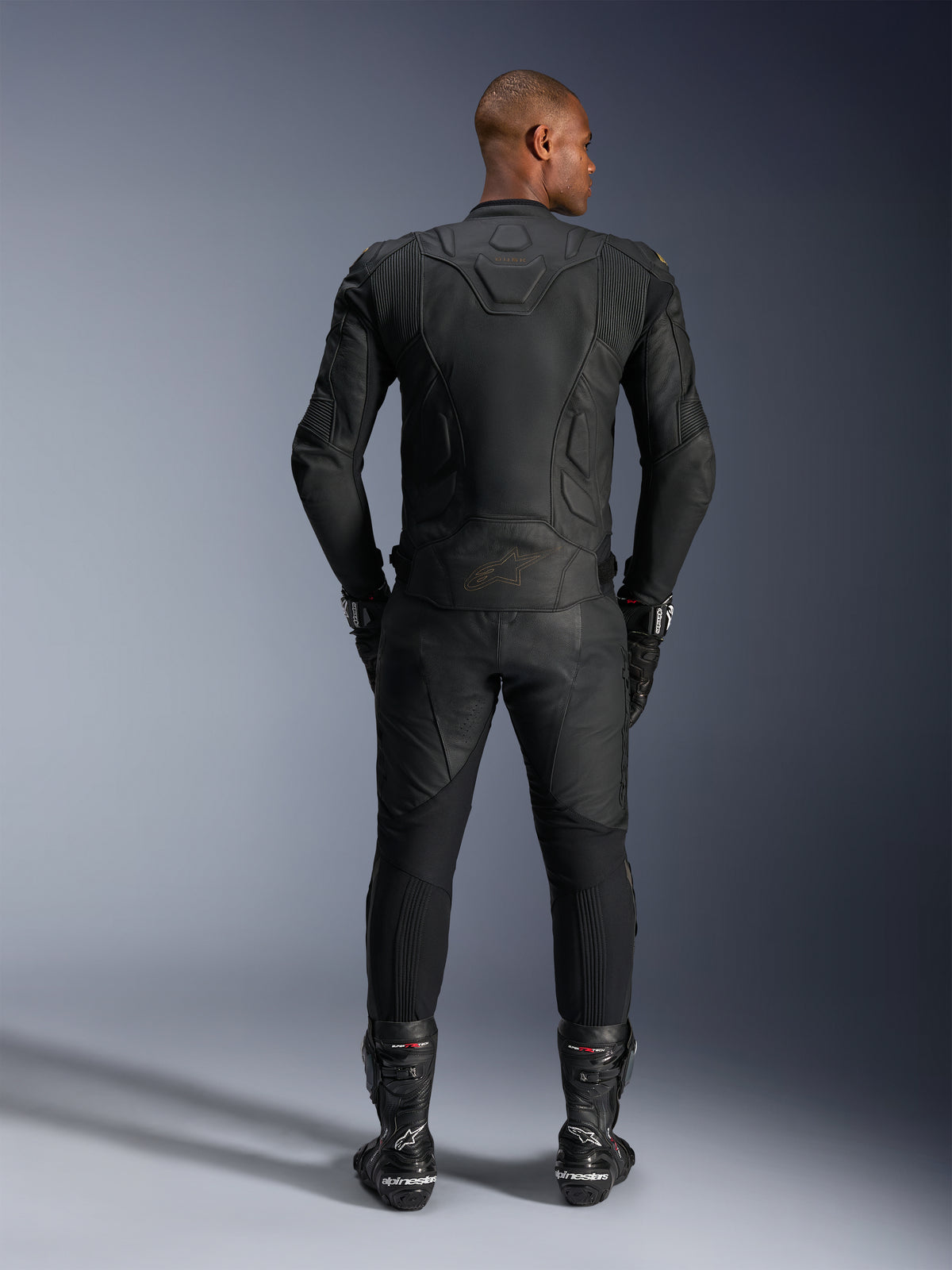 Alpinestars Dusk Leather Jacket, black bovine leather motorcycle racing jacket, rear view on a rider in protective gear.