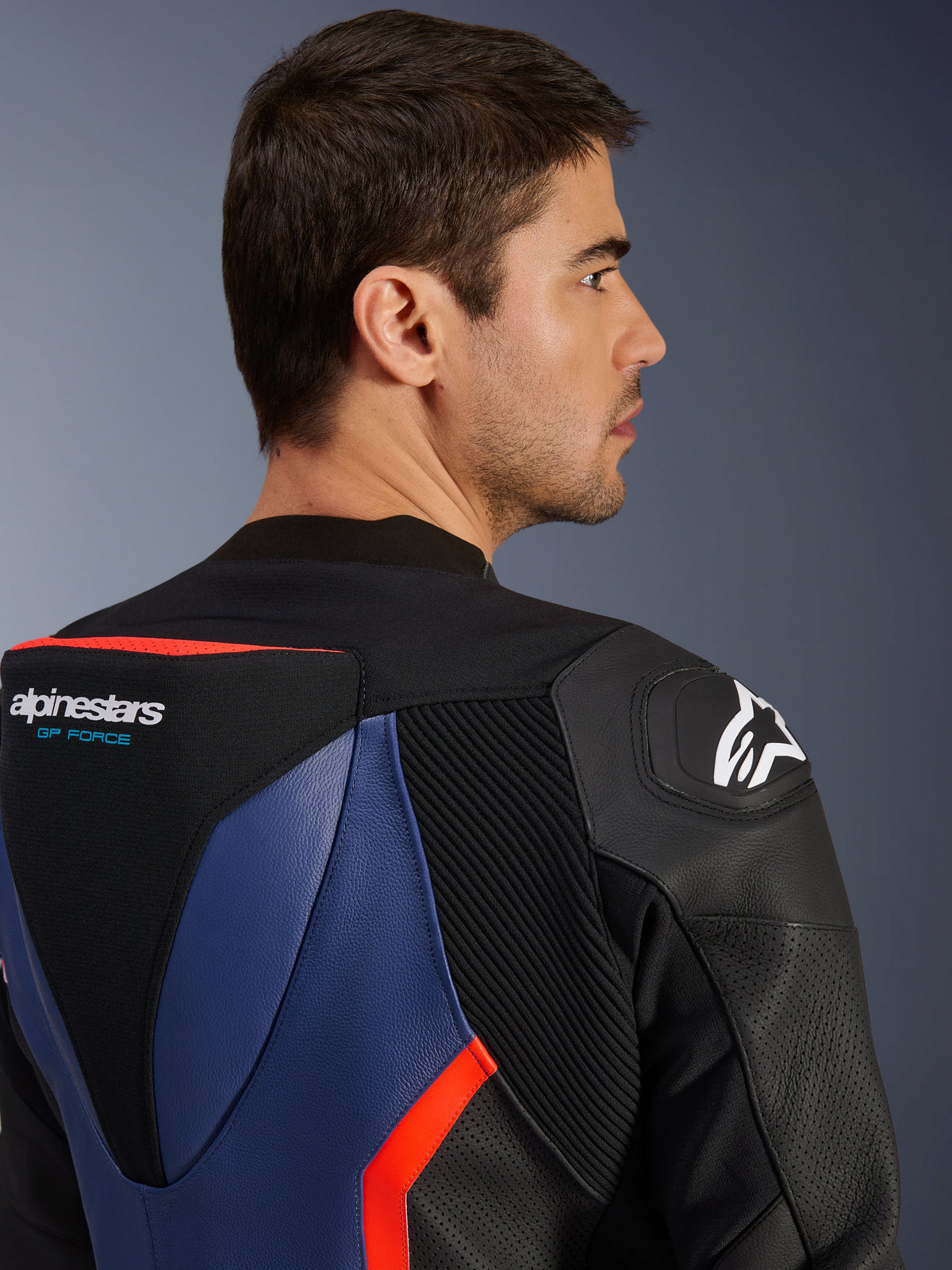 Alpinestars GP Force V2 Leather Suit - 2Piece, close-up of upper back and shoulder, aerodynamic speed hump with GP Force logo, DFS shoulder slider, black blue and red fluo bovine leather, perforated panels and accordion stretch zones, professional racing gear