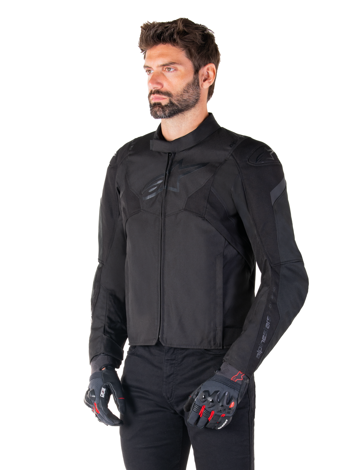Male rider wearing the Alpinestars T-Jaws V4 Waterproof Jacket in Black Black, paired with black pants and protective gloves, featuring a sleek sport fit, tonal Alpinestars logos on the chest and shoulders, and a high-performance textile construction.