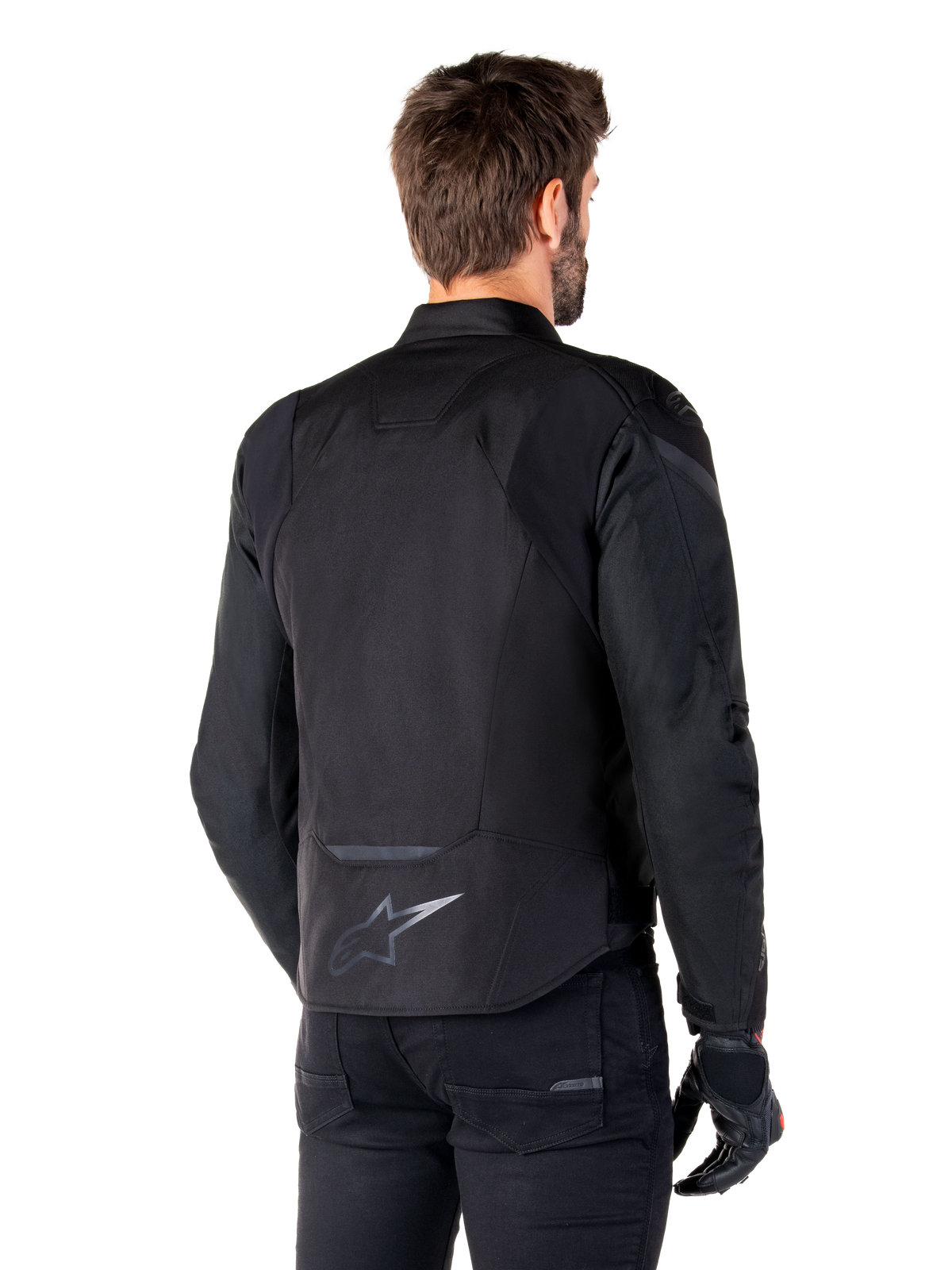 Alpinestars T-Jaws V4 Waterproof Jacket, Black, back view on model, featuring a reflective Alpinestars logo on the lower back, extended rear for coverage, sporty textile design with tonal panels, worn with black motorcycle gloves