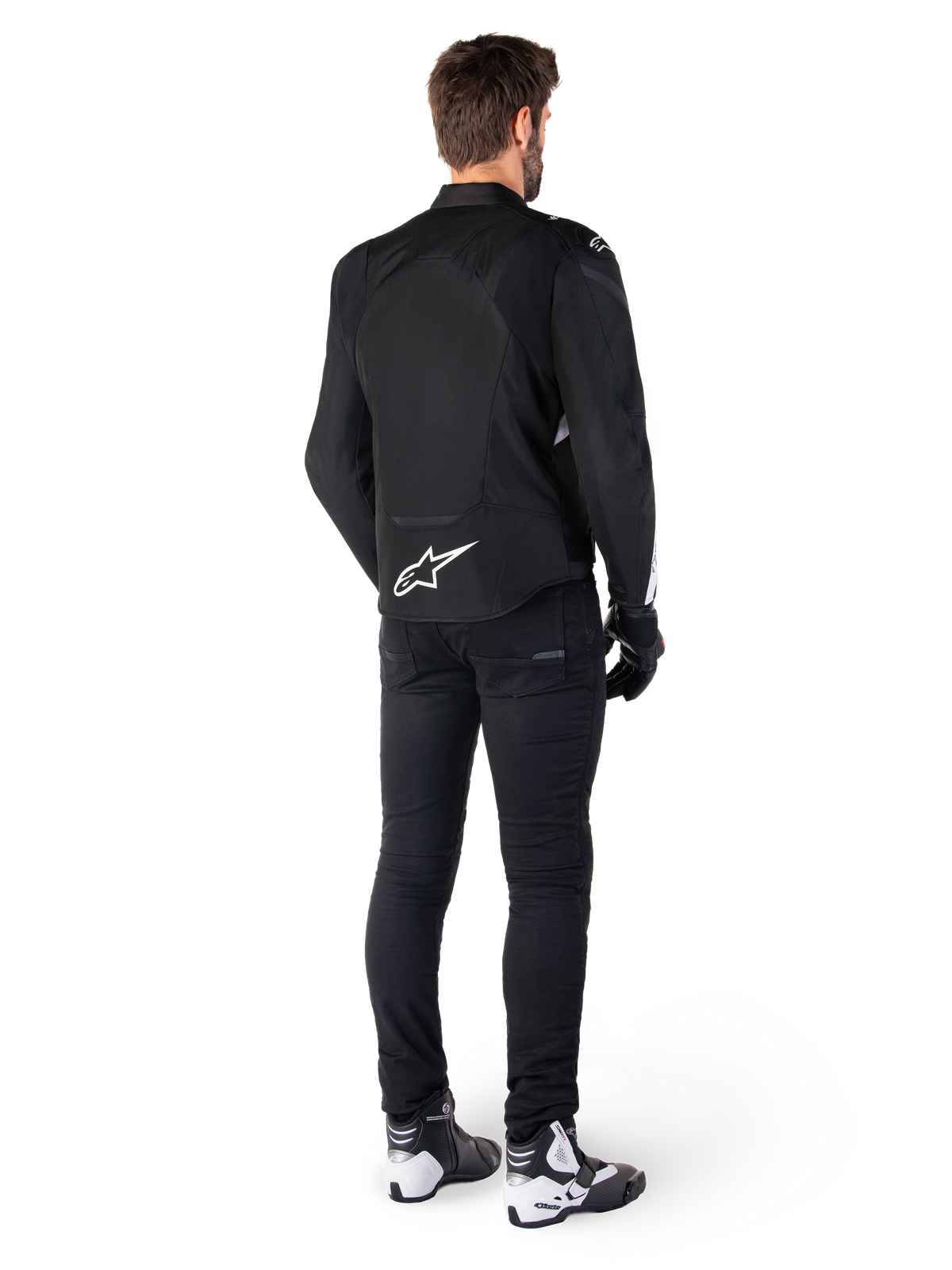 Alpinestars T-Jaws V4 Waterproof Jacket, Black and White, rear view showing white star logo on lower back, worn by model with black riding pants, black gloves, and white and black motorcycle boots.
