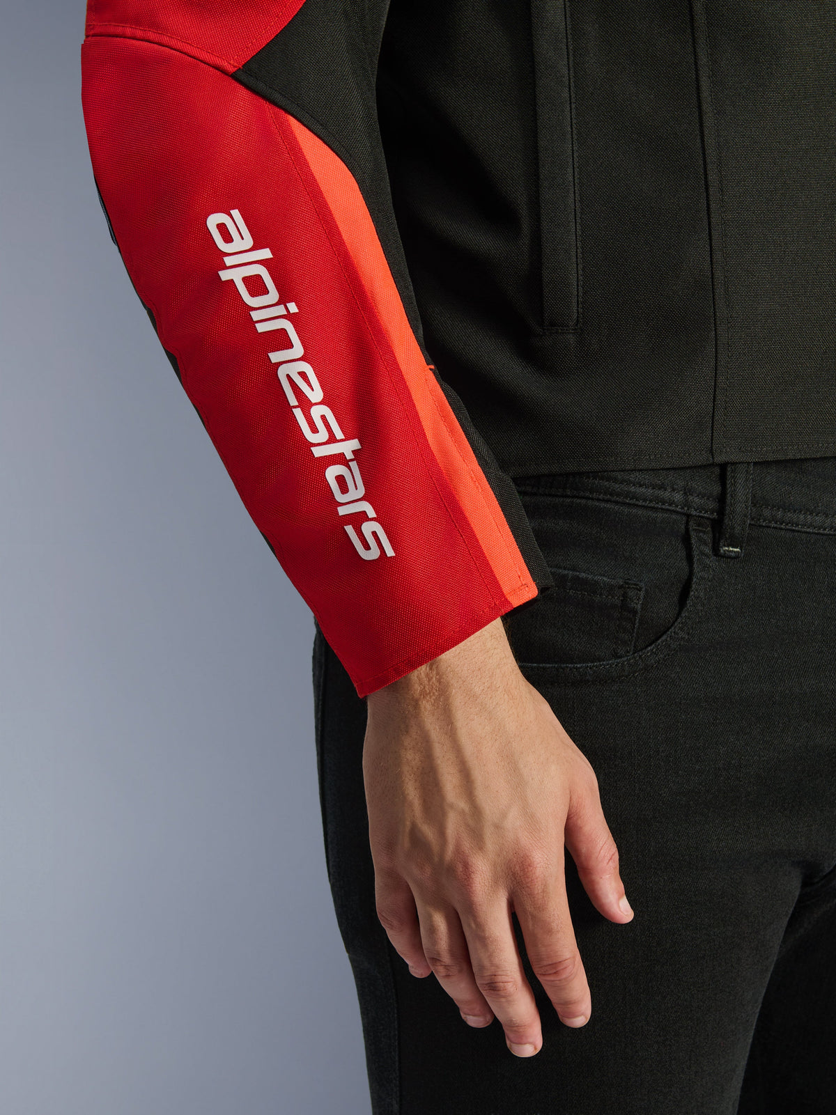 Alpinestars T-SPS V2 Waterproof Jacket, Motorcycle Jacket, Black and Red, close-up of the sleeve featuring a white vertical brand logo on a red panel, durable textile construction with a sport-inspired design.