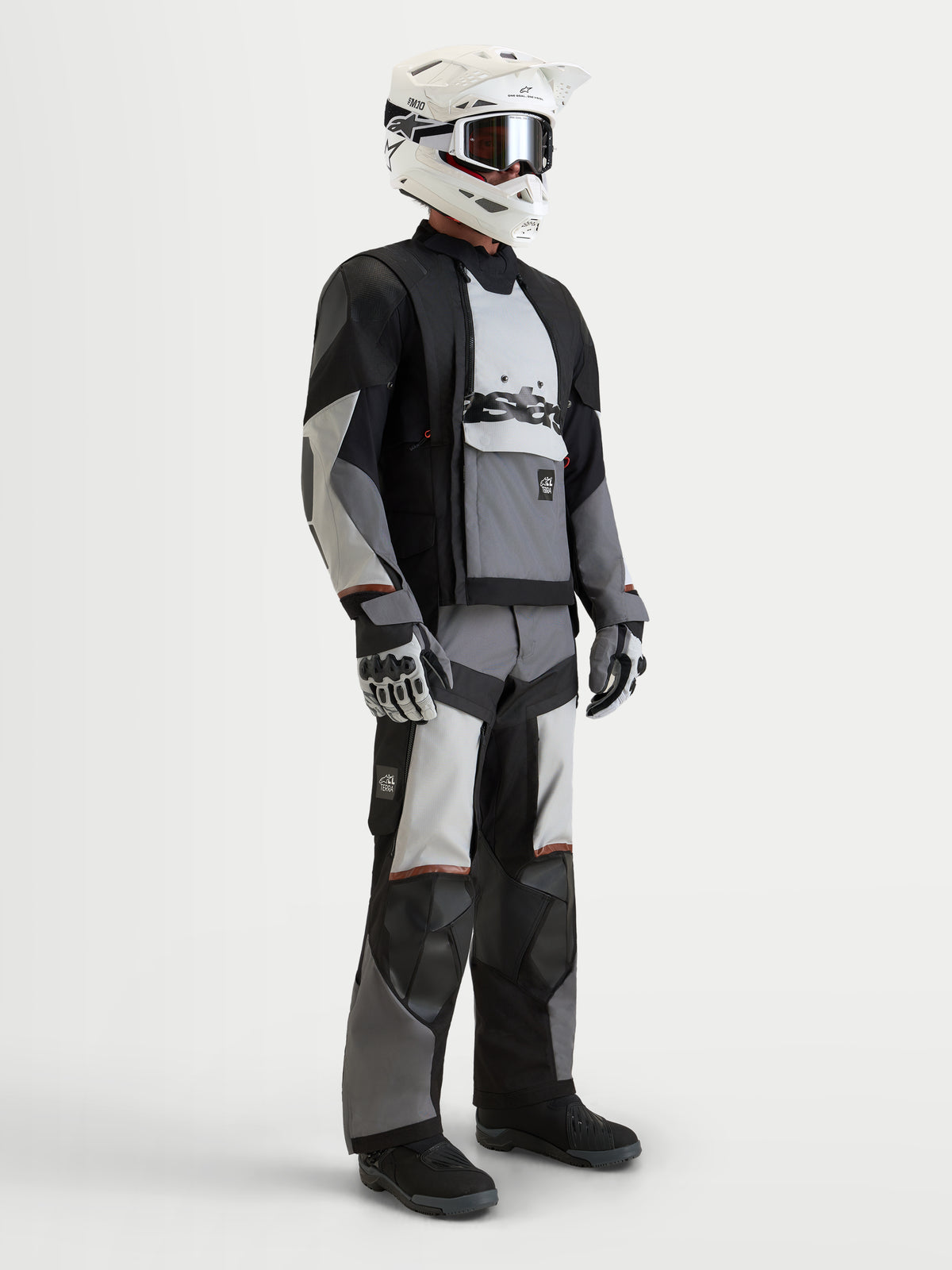 Alpinestars Harok V2 Drystar Jacket, Men's adventure motorcycle jacket in dark gray, ice gray, and black, worn with matching riding gear, helmet, and gloves, featuring all-terrain modular ventilation and waterproof construction