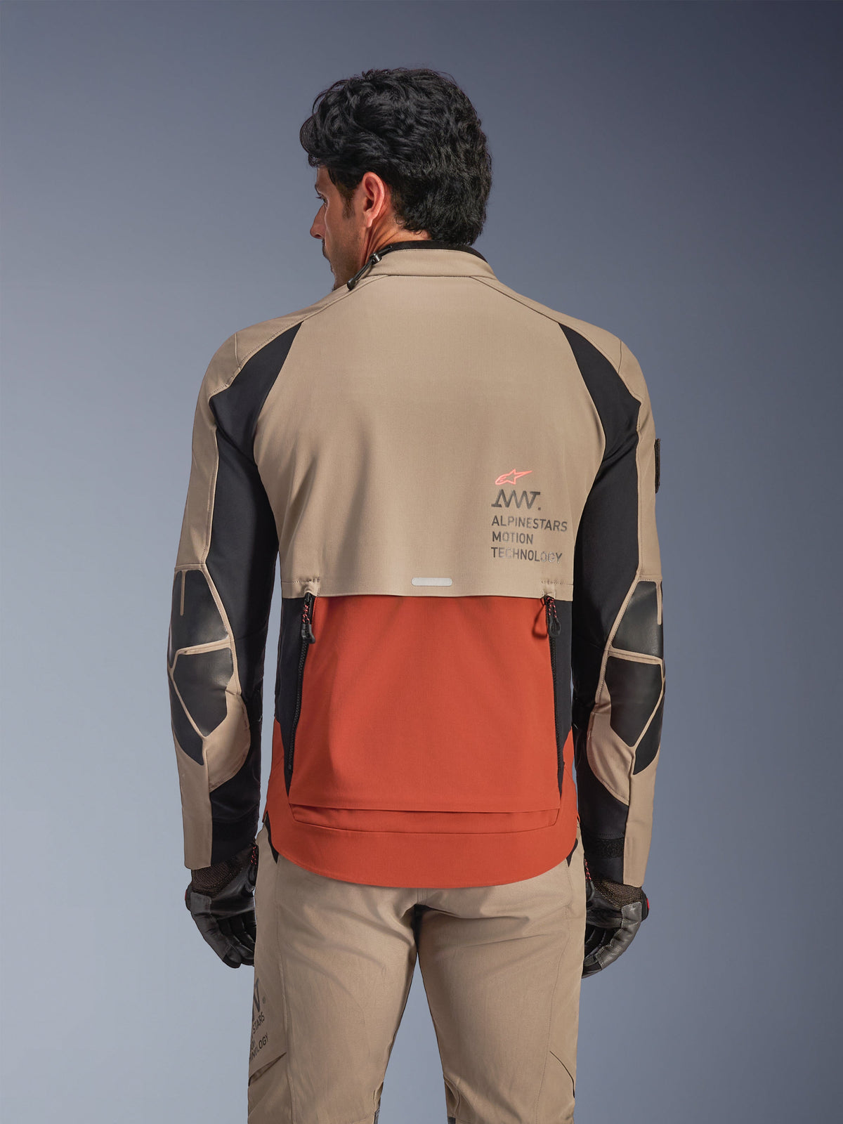 Alpinestars AMT-8 Stretch Drystar® XF Jacket, Walnut Rust Black, rear view on model, highlights the shingle design back exhaust in rust, walnut tan upper sections, black accents on sleeves, and Alpinestars Motion Technology branding