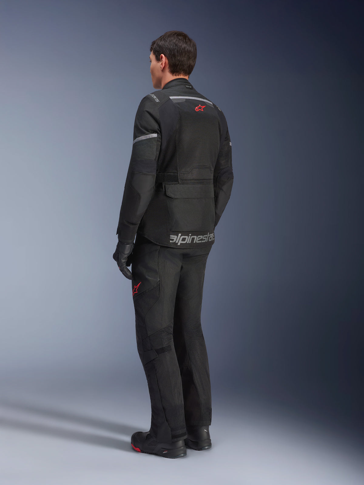 Alpinestars Andes Air Drystar® Jacket, Black, rear view on a rider, featuring extensive mesh panels for ventilation, worn with matching adventure motorcycle pants and boots, showcasing the road-oriented touring design and branding.