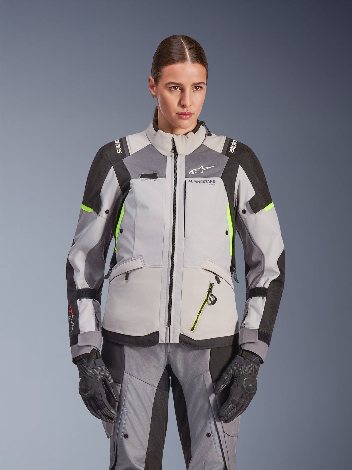 Alpinestars Woman Stella Andes V4 Drystar® Jacket, Ice Gray and Dark Gray with Yellow Fluo accents, adventure touring motorcycle jacket, worn with matching pants and gloves, featuring protective textile construction and Alpinestars branding.