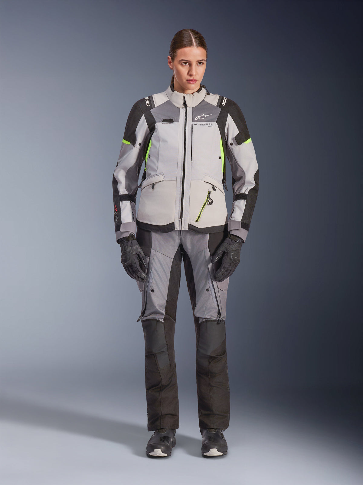 Alpinestars Woman Stella Andes V4 Drystar® Jacket, Ice Gray and Dark Gray with Black and Yellow Fluo accents, worn with matching riding pants and gloves, waterproof adventure-touring gear for women