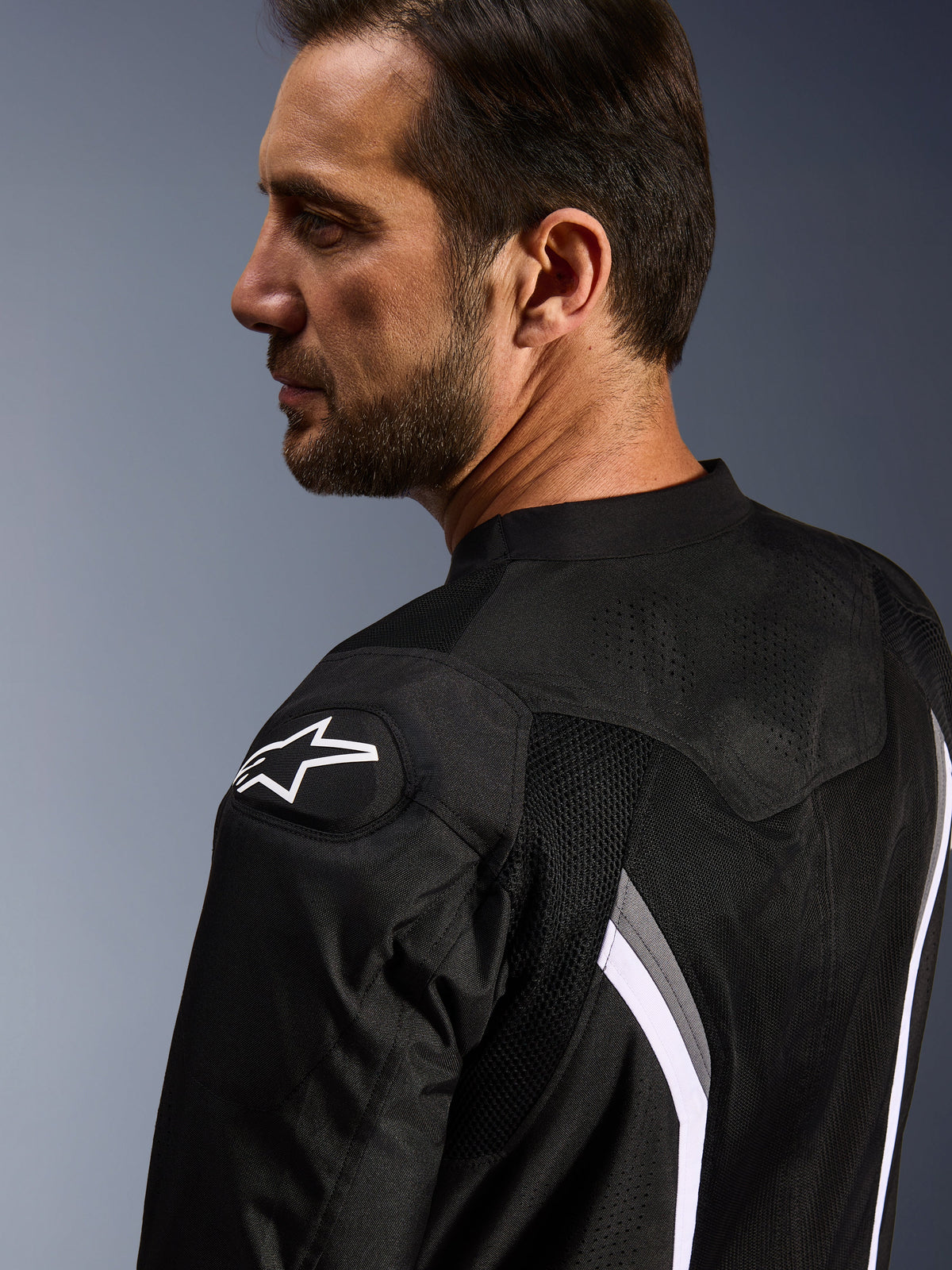 Alpinestars AST V3 Air Jacket, Motorcycle Air Jacket, Black Dark Gray and White, close-up view from behind showing white star logo on shoulder and laser-perforated mesh panels for ventilation.