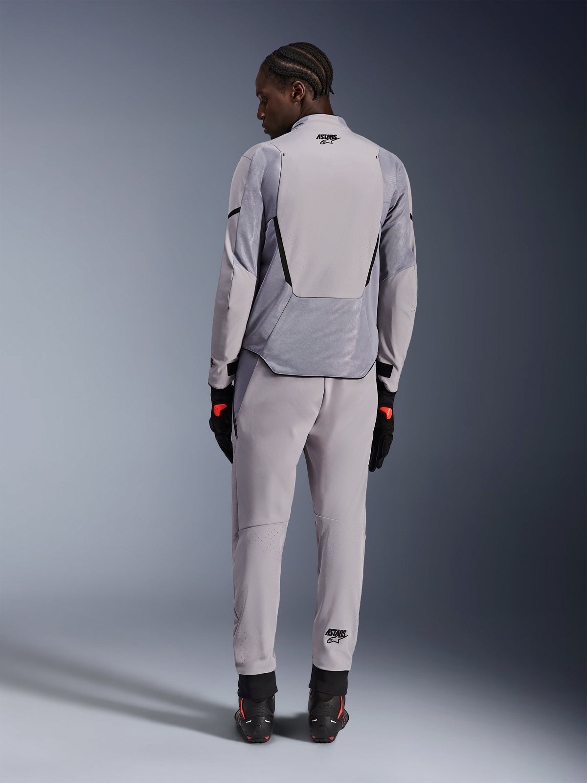 Alpinestars Aeroshell Airflow Jacket, Mid Gray Anthracite, back view on a model, featuring technical mesh panels and laser-perforated ventilation zones, worn with matching gray pants and black motorcycle gear, sport-cut design for high performance.