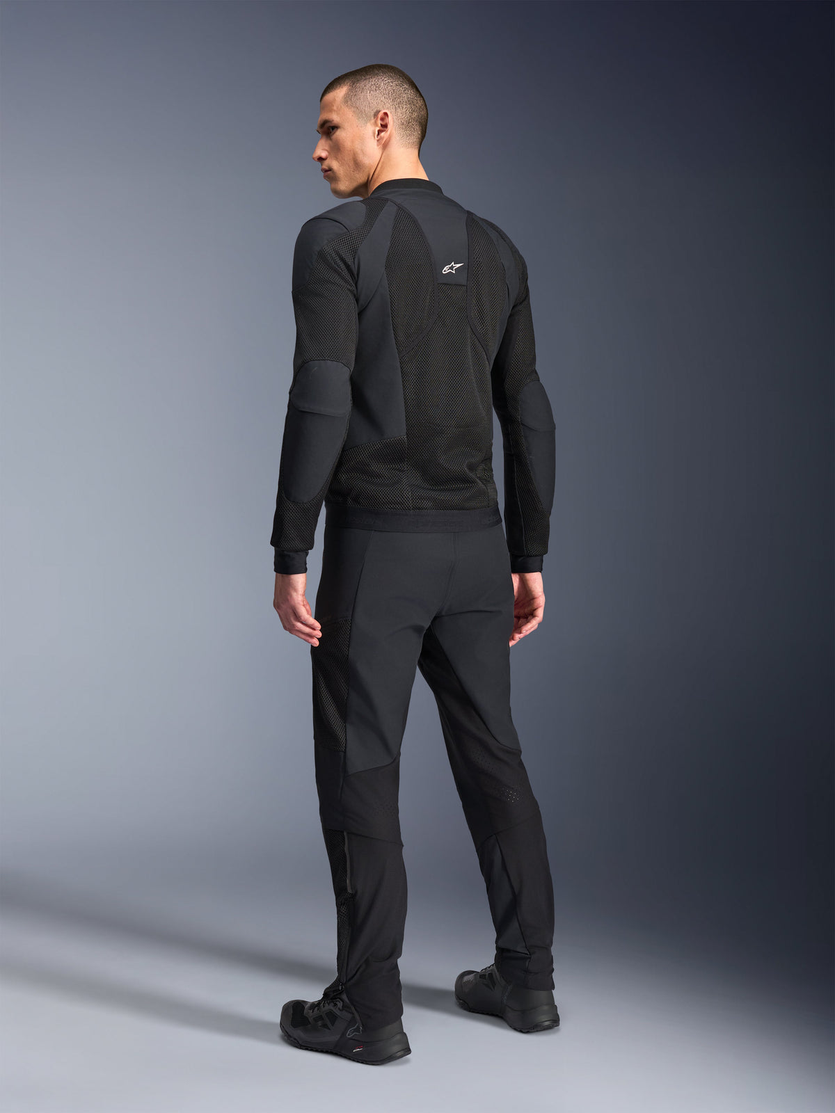 Alpinestars Troop-Air Pro Jacket, Black, technical armored air jacket shown from the back, featuring extensive mesh panels for airflow, paired with matching black technical pants and shoes.