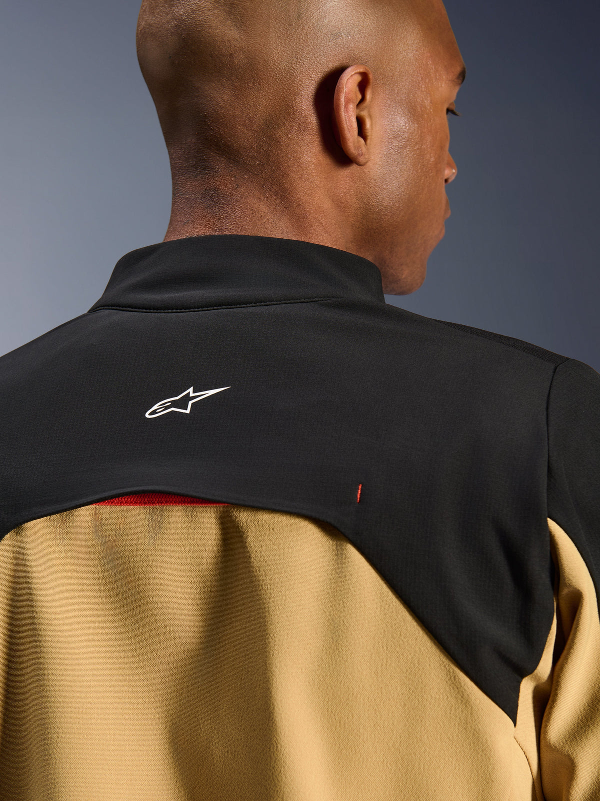 Alpinestars Provoke Jacket, Urban Motorcycle Jacket, Black and Camel, close-up of the upper back and collar area featuring a white Astars logo on a black yoke with tan lower panels, contemporary outdoor-inspired technical design
