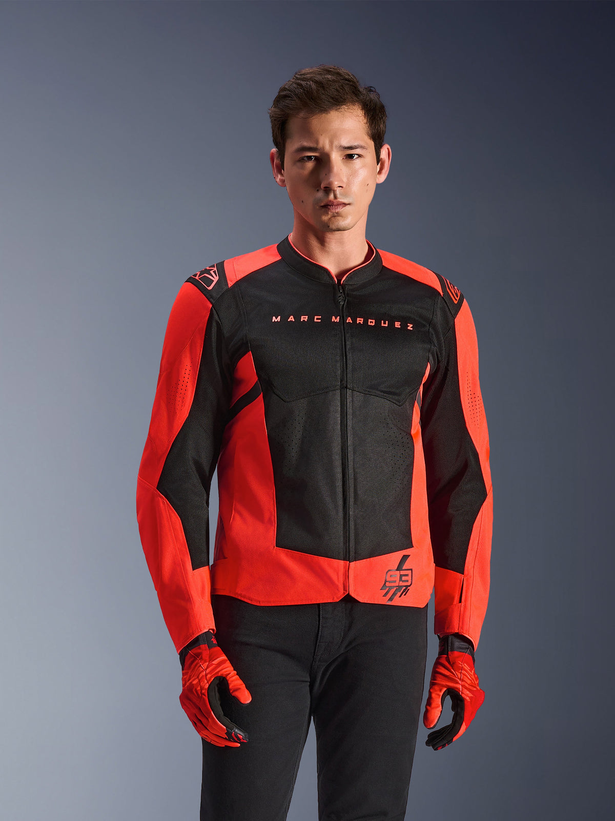 Alpinestars MM93 T-SPS Air V2 Jacket, Motorcycle Jacket, Red Fluo and Black, worn by a model with matching red gloves and black pants, featuring 'Marc Marquez' branding on the chest and '93' logo, sporty mesh construction