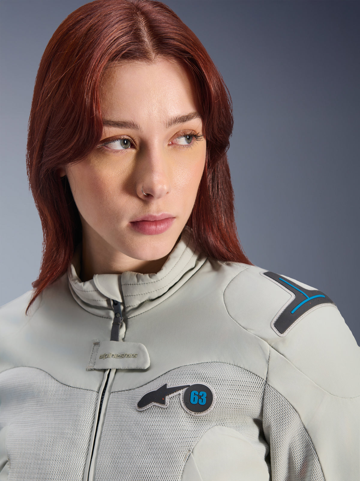 Woman wearing Alpinestars Stella Circal-1 Air Jacket, Women's Textile Motorcycle Jacket, Metal Gray and Methyl Blue, close-up lifestyle shot featuring mesh airflow panels, padded collar, and Alpinestars logo patch with the number 63.