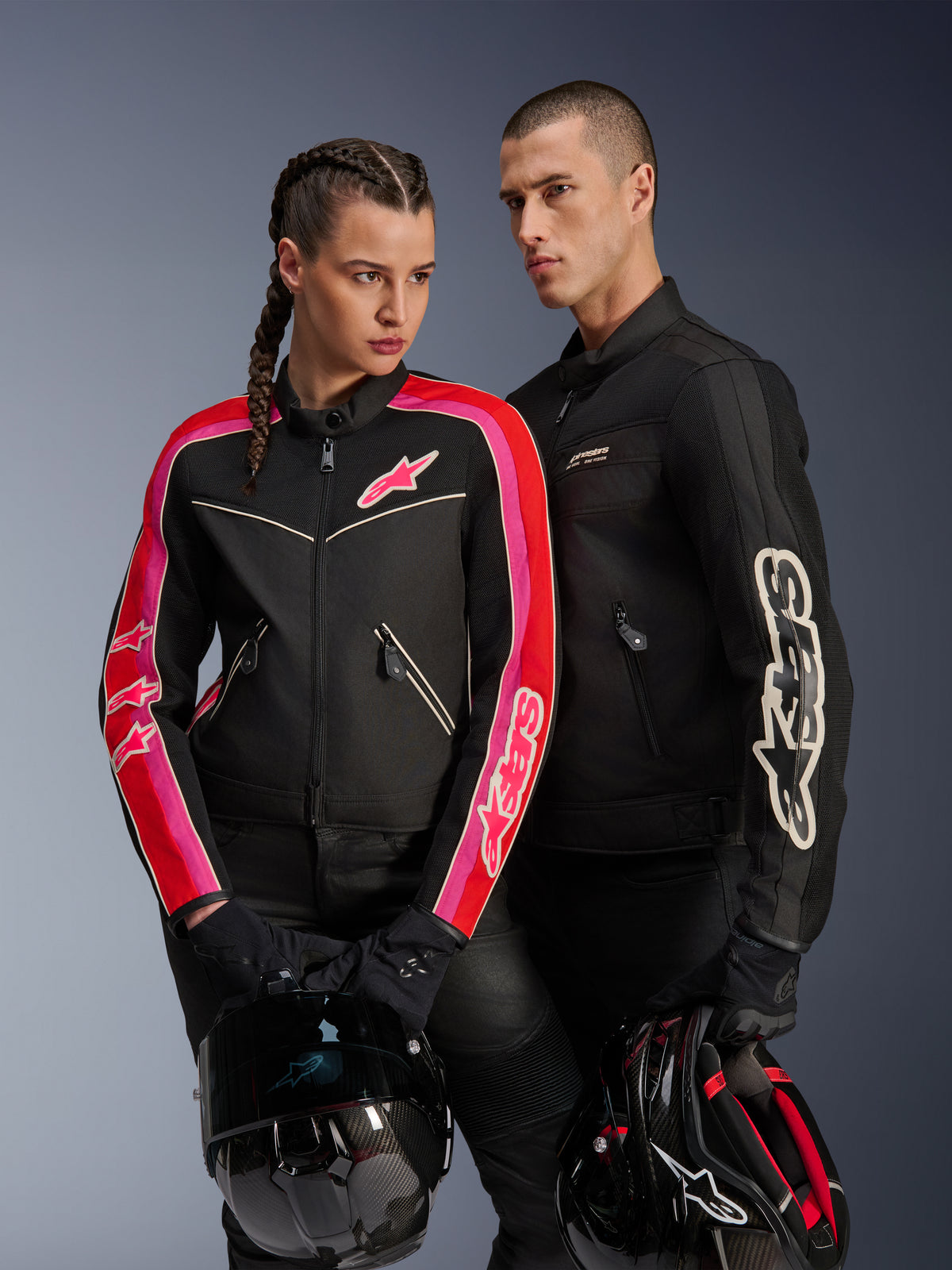 Alpinestars Stella T-Dyno Air Jacket on woman in Black Bright Red Fuchsia, paired with men's black Dyno Air Jacket, both riders holding motorcycle helmets, studio shot of urban contemporary motorcycle gear