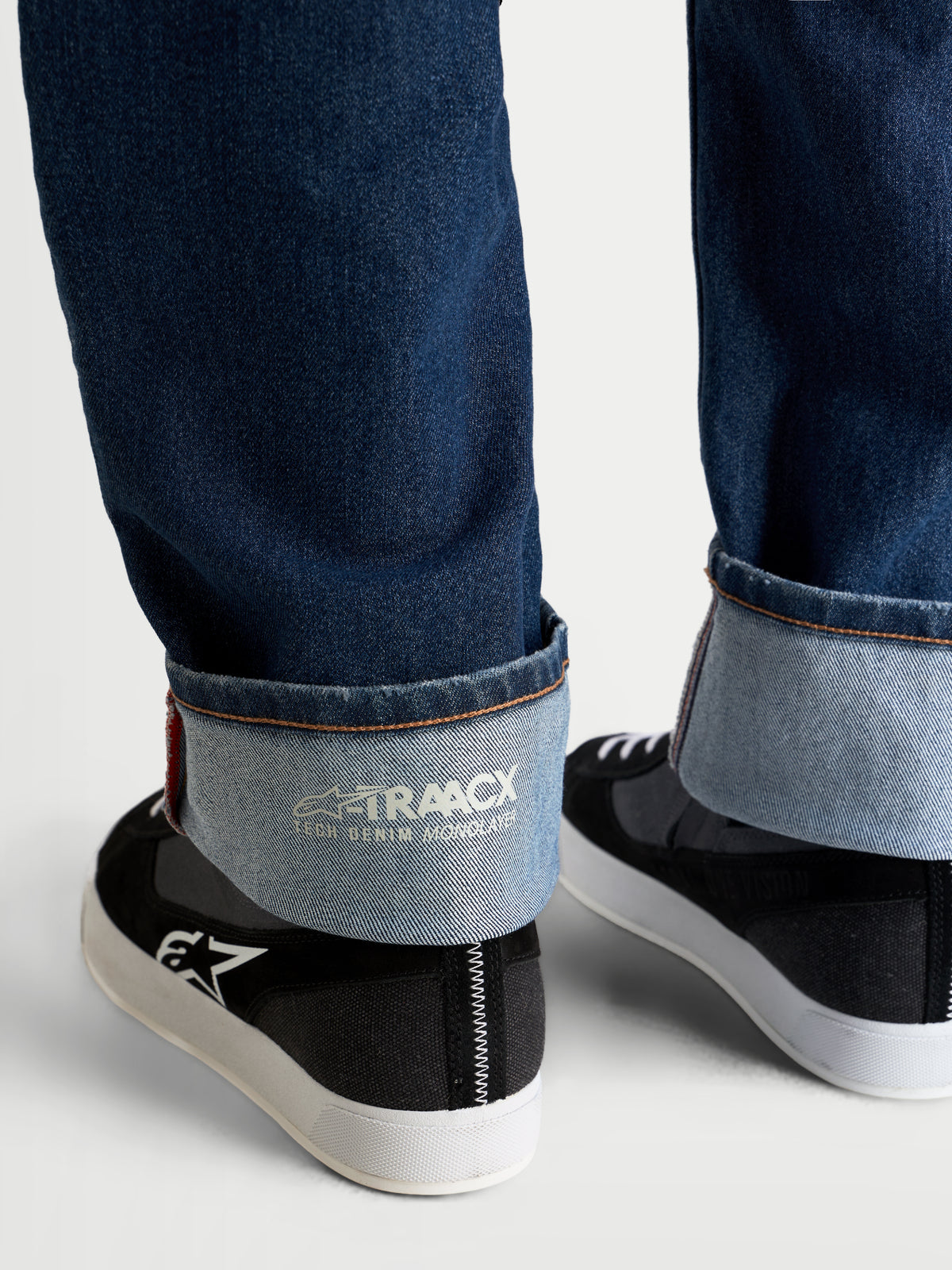 Alpinestars Flex-AST 8 Denim Pants Short, urban motorcycle riding jeans, medium blue, detailed view of the cuffed hem showing A-TRAACX technical denim branding and footwear on a model