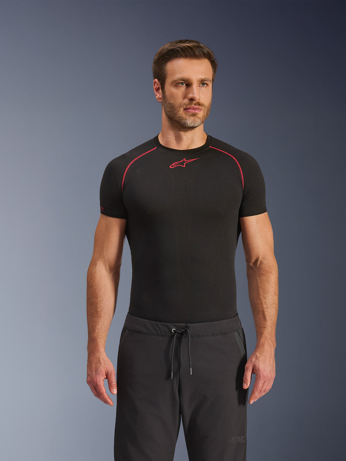 Alpinestars Aeroshell Airflow Pants, Black motorcycle pants, lightweight softshell textile, featuring a drawstring waistband and laser-perforated ventilation, worn with a black Alpinestars base layer shirt