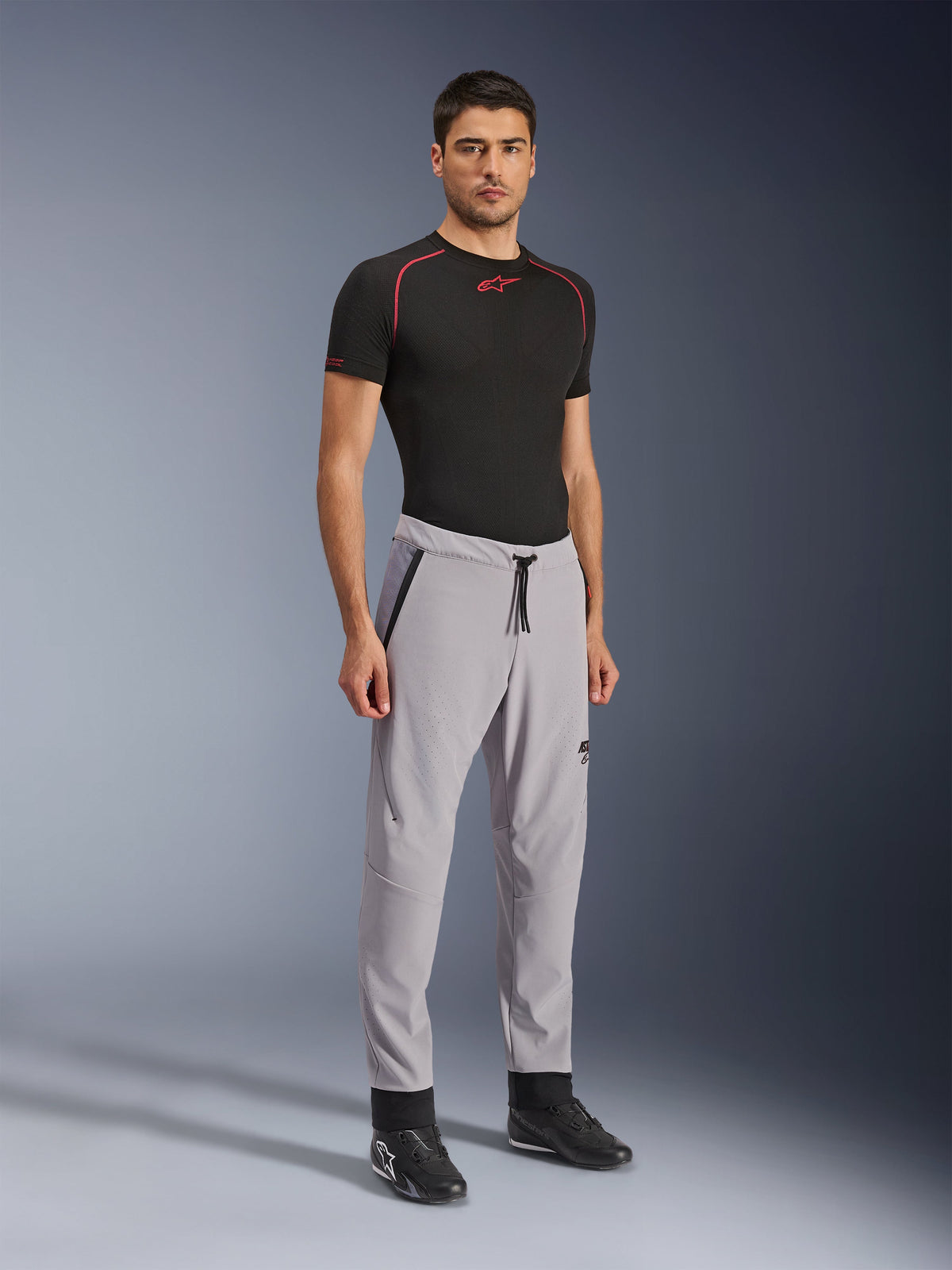Alpinestars Aeroshell Airflow Pants, Motorcycle Pants, Mid Gray, worn by a model with a black technical t-shirt and black riding shoes, featuring laser-perforated ventilation zones, drawstring elastic waistband, and a streamlined sport fit.