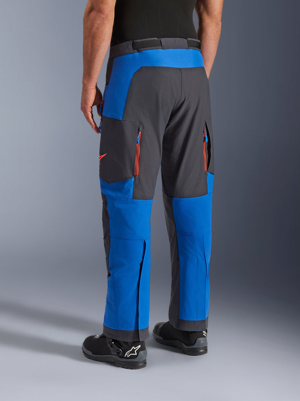 Alpinestars Maxdura Dual Pants, Royal Blue and Deep Gray, rear view showing zippered pockets and ventilation zones, over-boot design worn with black Alpinestars boots, durable adventure and dual-sport riding gear