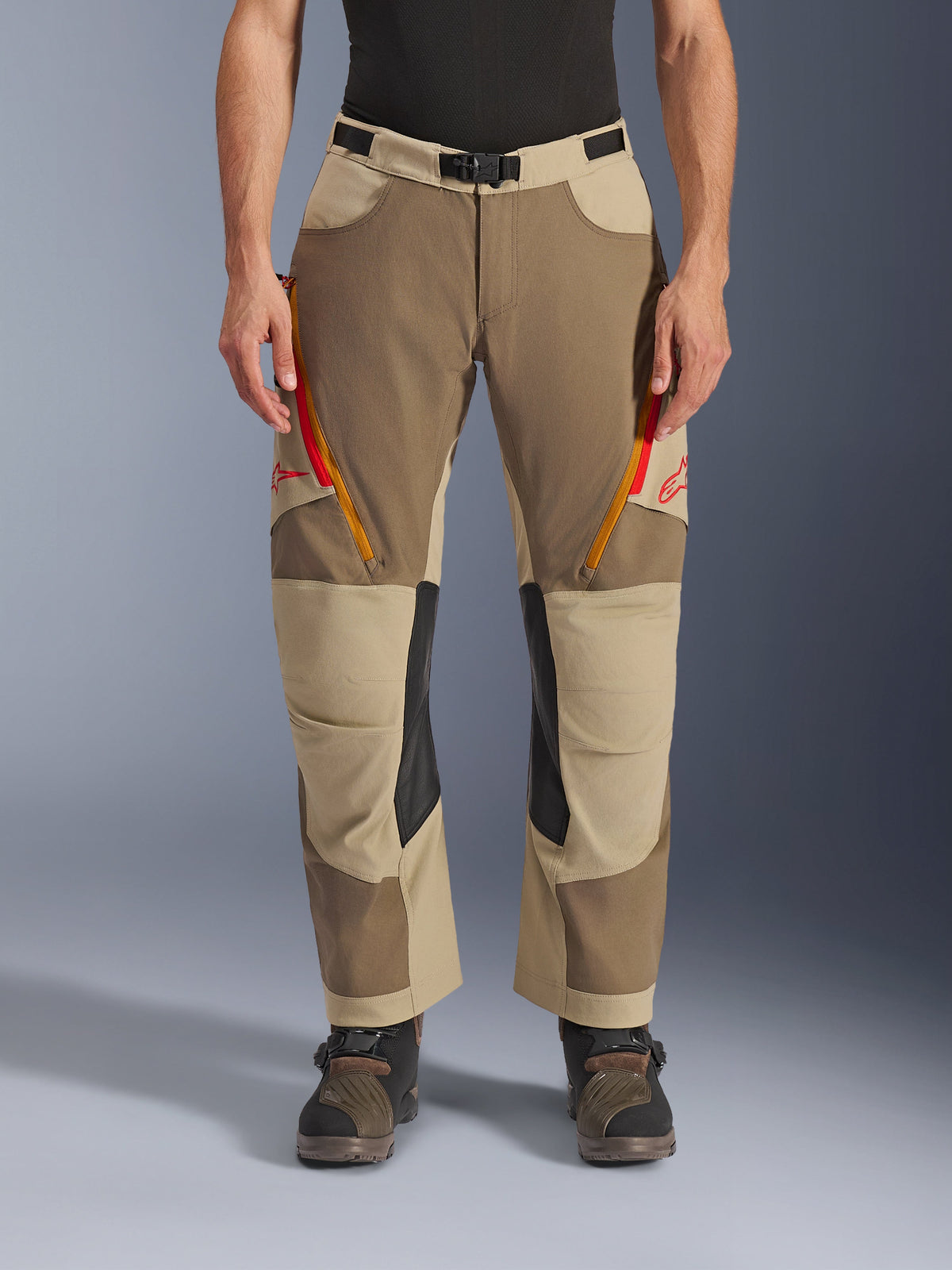 Alpinestars Maxdura Dual Pants, Walnut Aluminum, adventure motorcycle pants featuring red and orange zippered thigh vents, black leather inner knee panels, worn with a black base layer and rugged boots, durable multi-tonal design for dual-sport riding