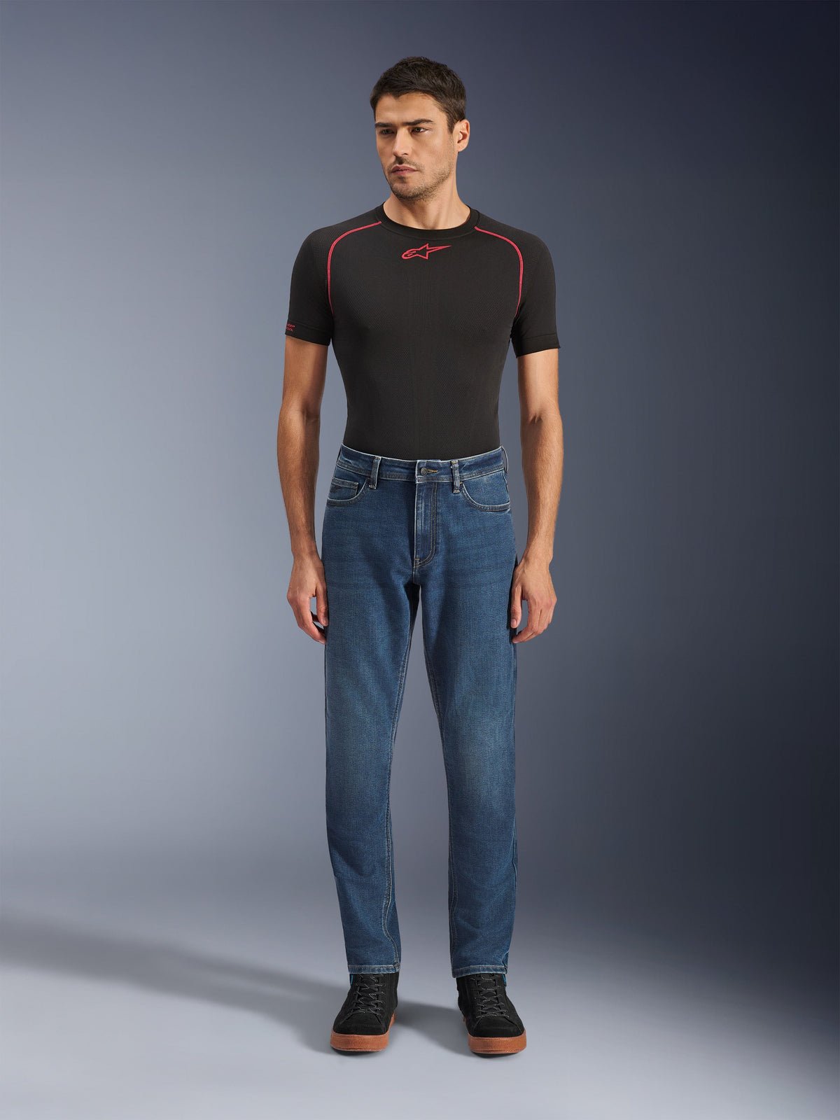Alpinestars Flex-AST 5 Denim Pants, Motorcycle Denim Pants, Indigo Washed, worn with a black performance t-shirt and black sneakers, featuring a tapered fit and monolayer stretch denim construction for urban riding