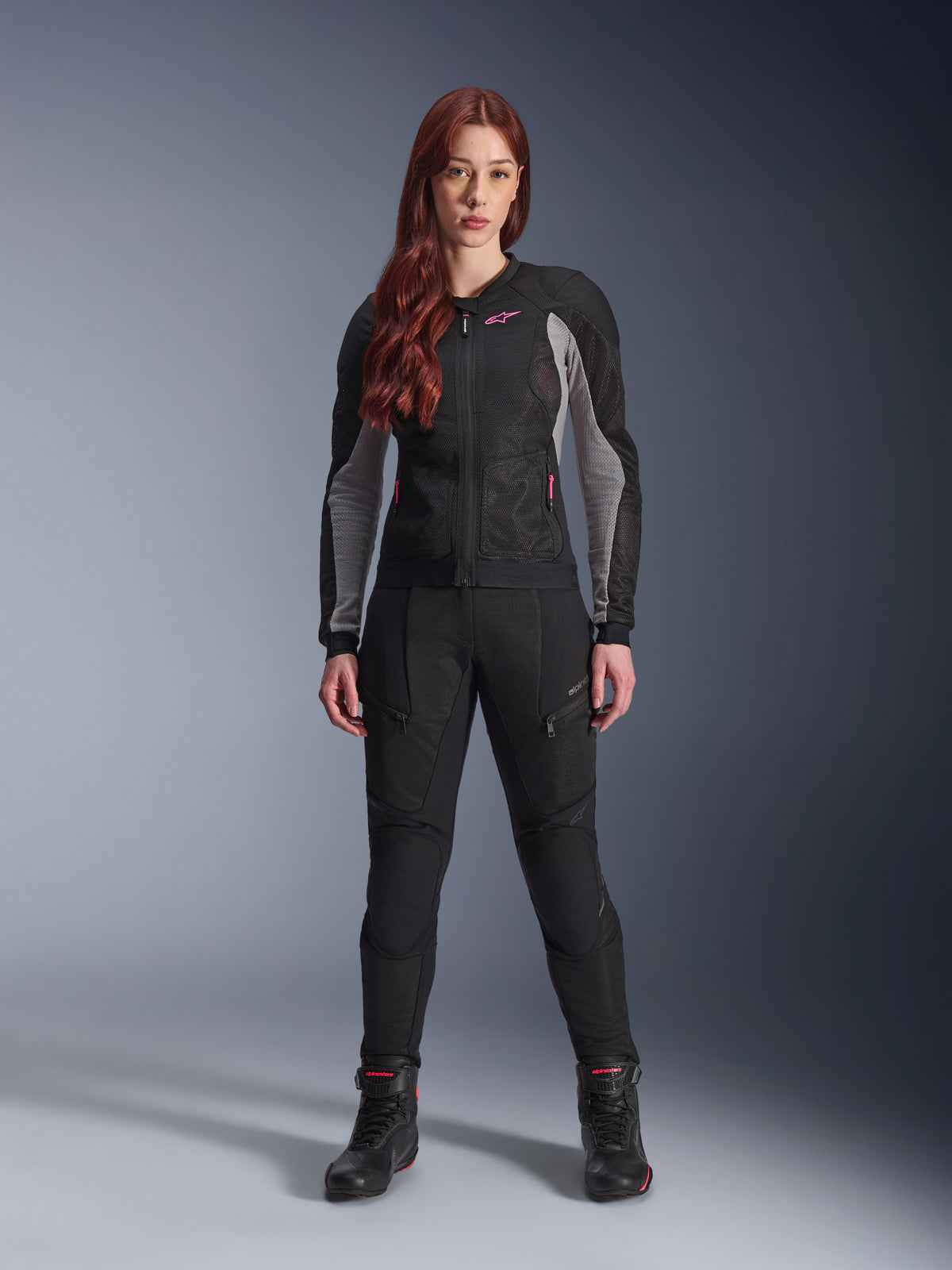 Alpinestars Stella Troop-Air Pants, Women's motorcycle riding pants in black, features mesh panels and zippered pockets, styled with a matching black and grey mesh jacket with pink accents and black riding boots, complete urban motorcycling outfit.