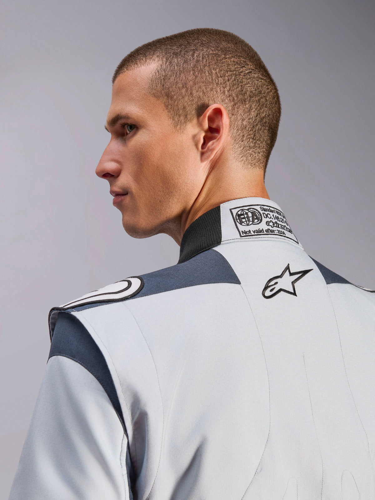 Alpinestars GP Pro Comp V2 FIA Suit in Silver and Gray, featuring an FIA certification label and embroidered logo.