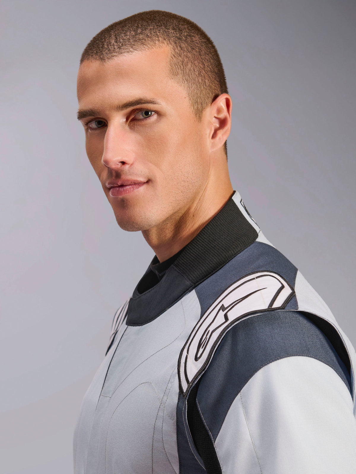 Alpinestars GP Pro Comp V2 FIA Suit, gray and black auto racing suit with high collar and white shoulder logo on male model.